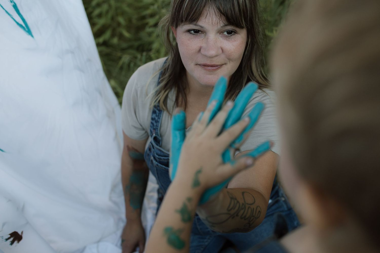 A mom and son giving each other a high-five with paint covered hands during a painting photo session by Courtice family photographer
