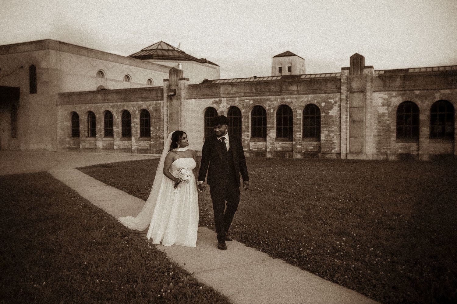 Couple walking in front of a heritage building in Toronto by candid wedding photographer Durham Region