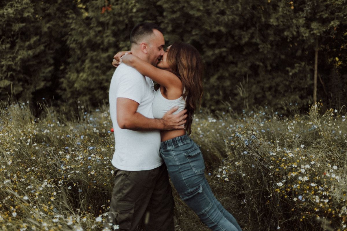 Couple sharing a kiss in a wildflower field, surrounded by colorful blooms by artistic family photographer Bowmanville, ON