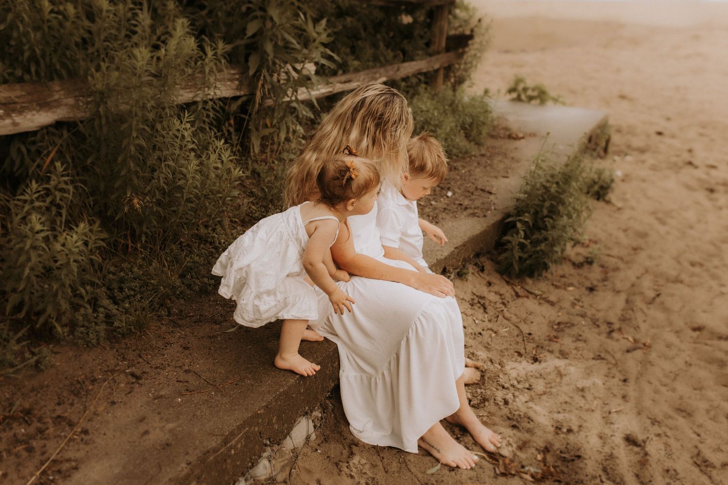 Mother cuddling her two children on a Lake Ontario beach during a family photography session in Durham Region