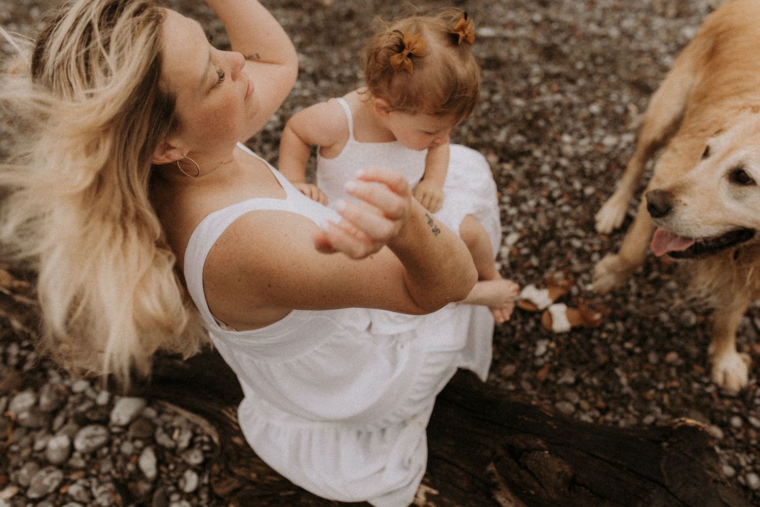 Mom enjoying the breeze in her hair with her daughter and sweet dog on a moody beach by Cobourg family photographer
