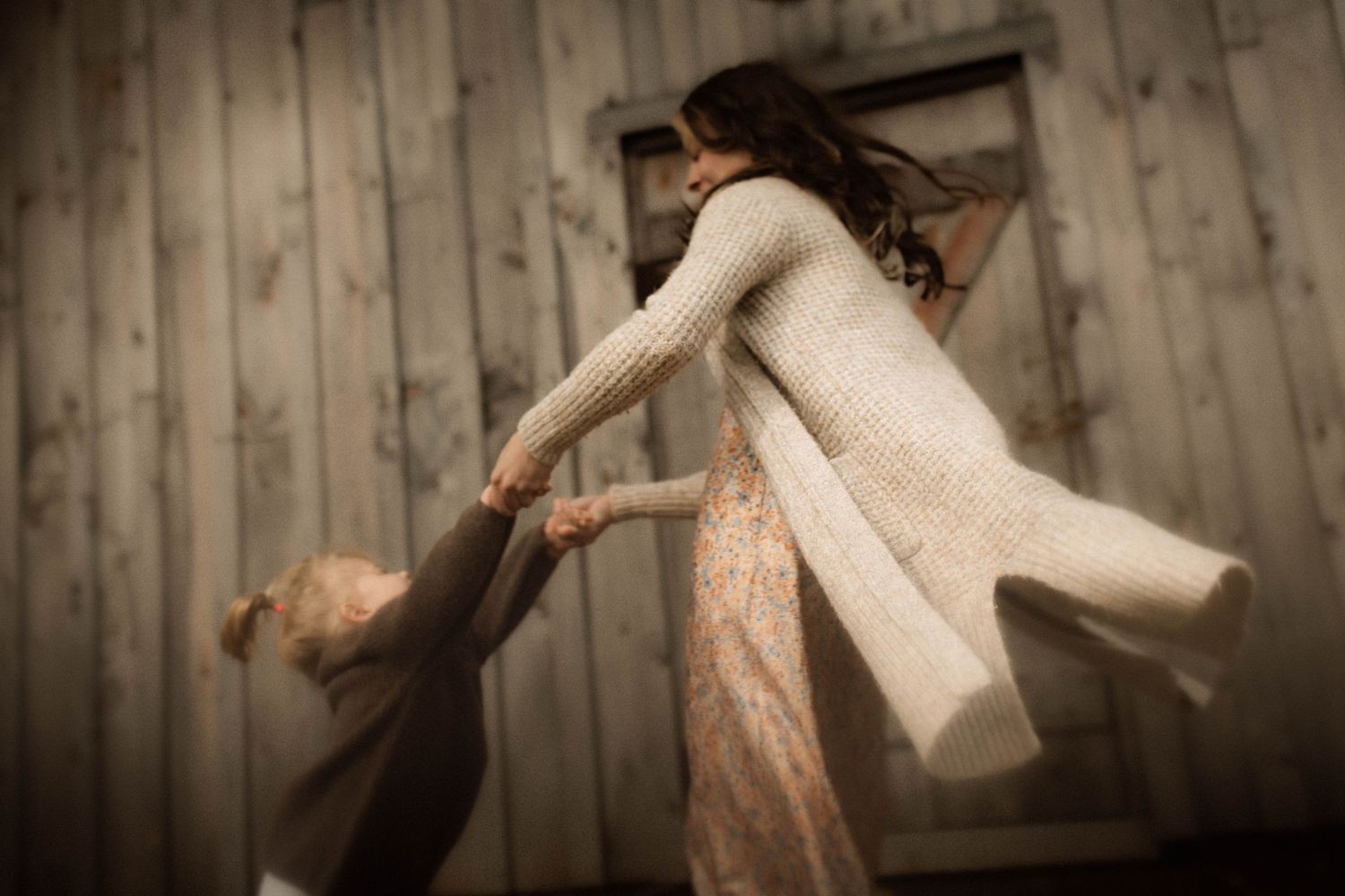 Mom and daughter playing Ring Around The Rosie in front of a barn by Bowmanville, ON family photographer.