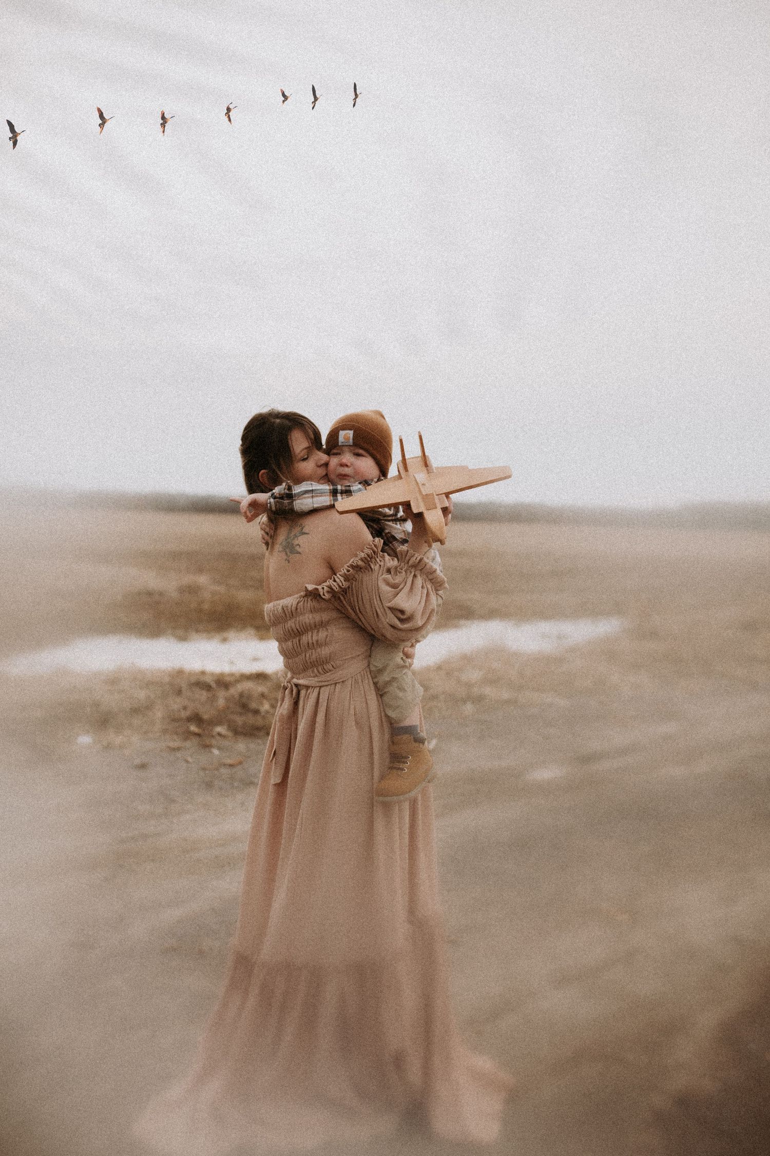 Motherhood session on a country road wearing a pale rose dress and holding her toddler in her arms by Bowmanville, ON family photographer.