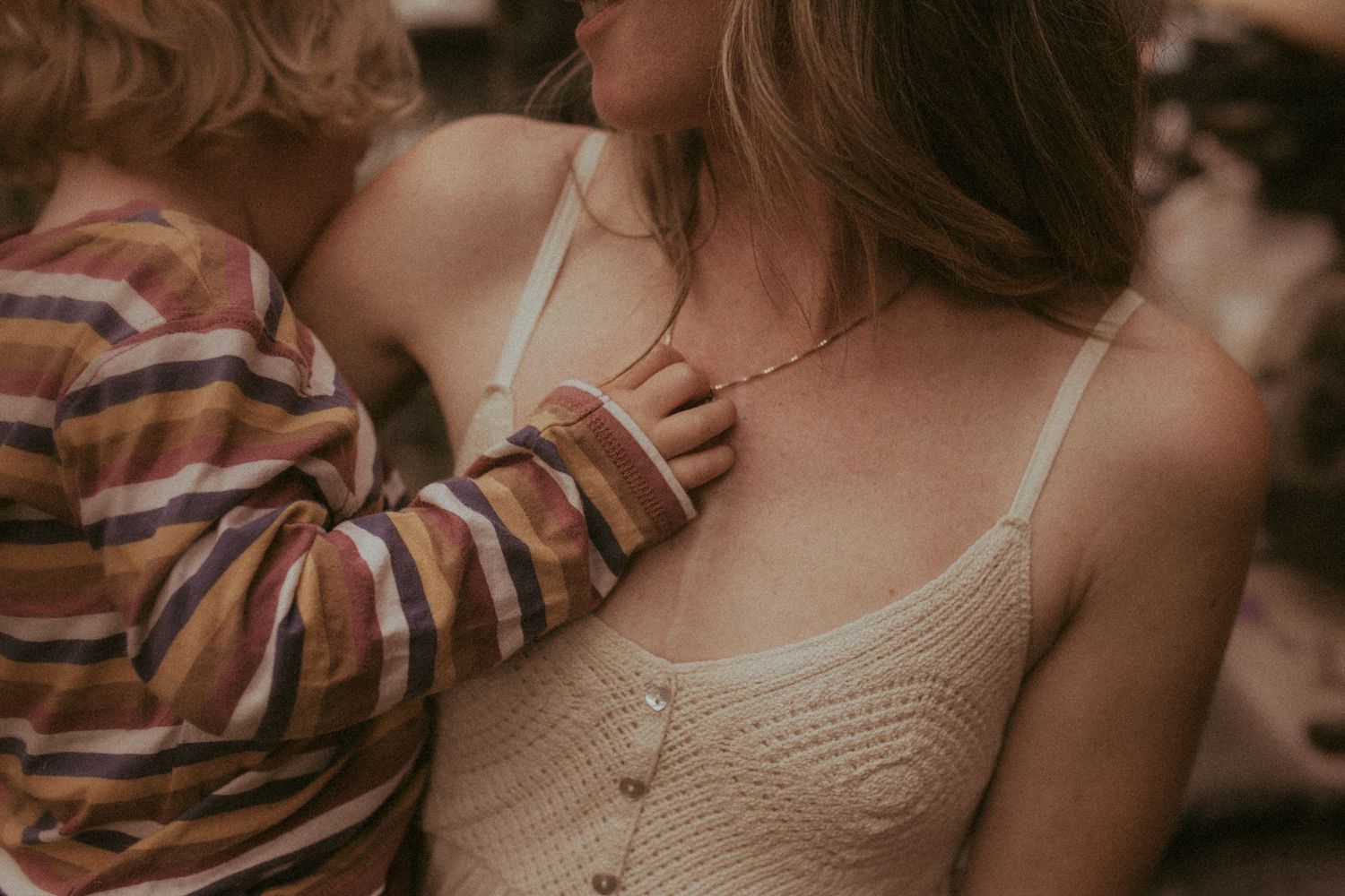 A close-up image of a boy clutching his mom's necklace as she holds him in her arms by a Durham Region family lifestyle photographer.