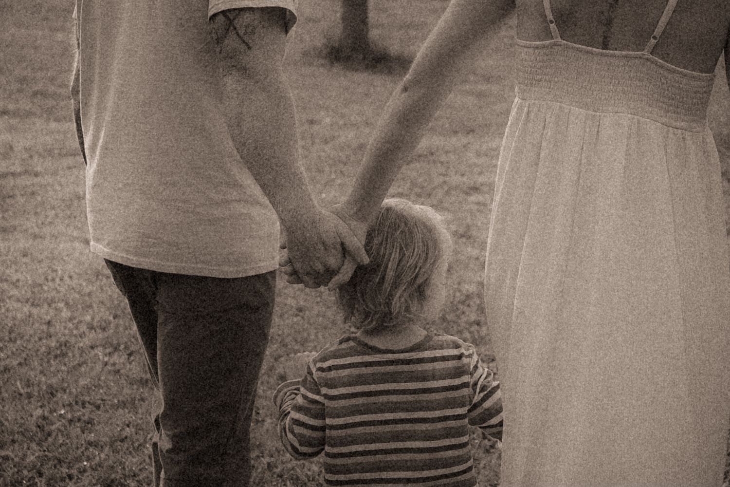 A couple holding hands as they walk as their son tries to get in the middle during a Durham Region Family Lifestyle photography session.