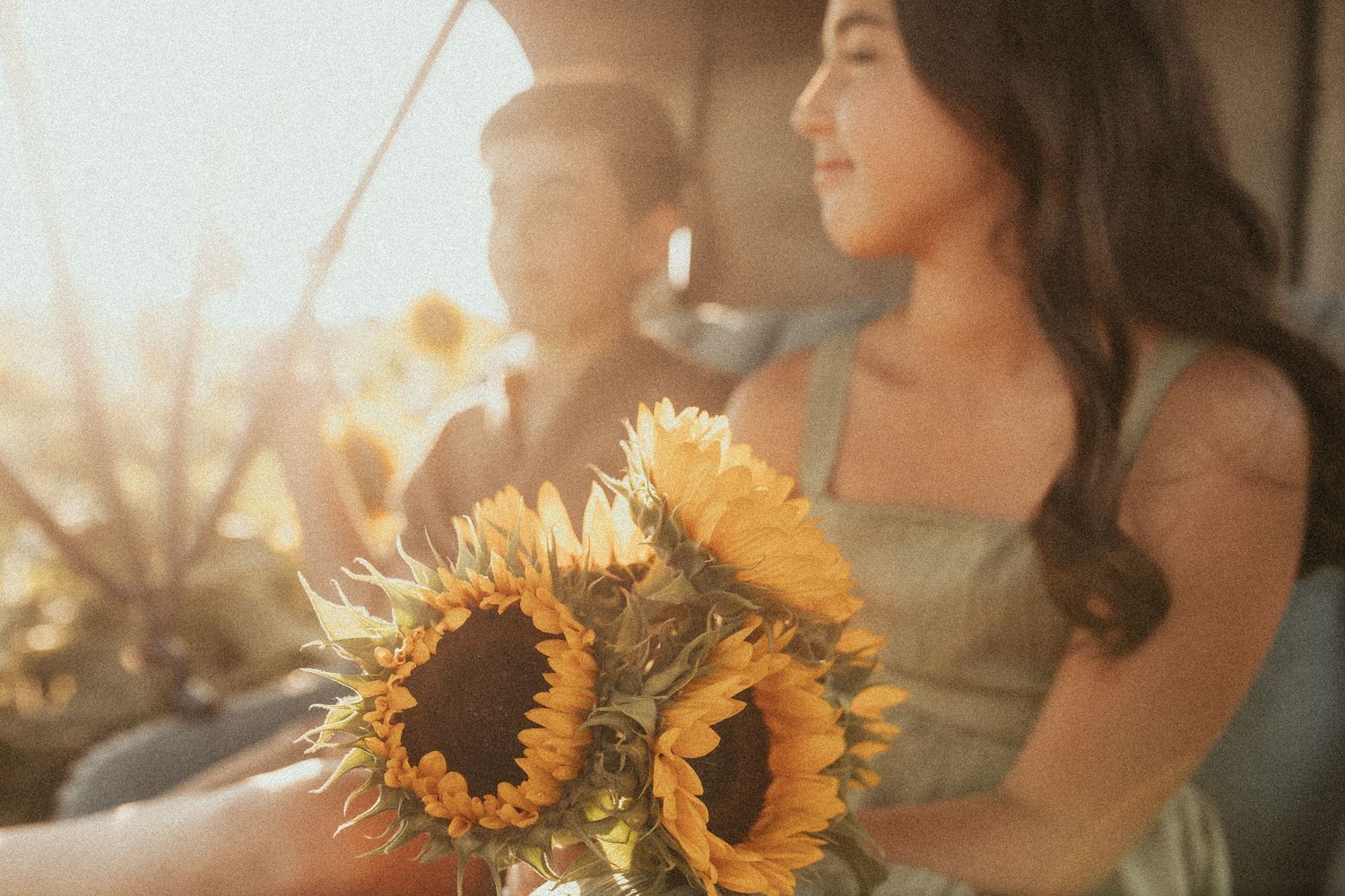 A photo of a brother and sister holding a bouquet of sunflowers in a carriage at sunset by Durham Region family photographer