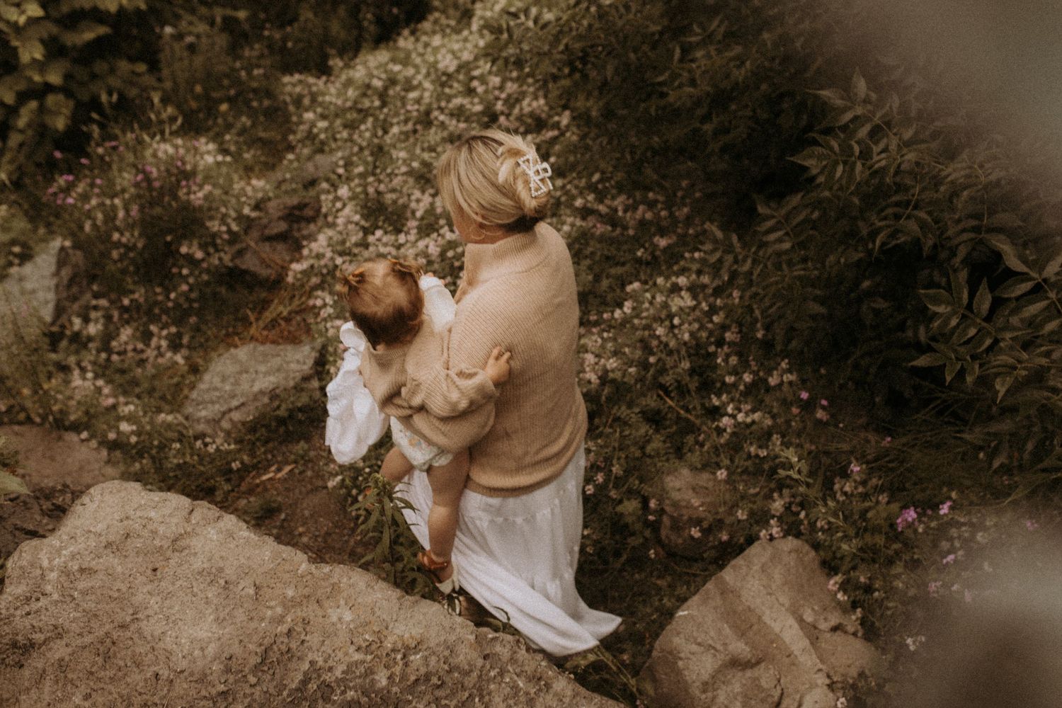 Photo of mom carrying her little girl down a rocky hill towards a beach in Cobourg by Cobourg family photographer