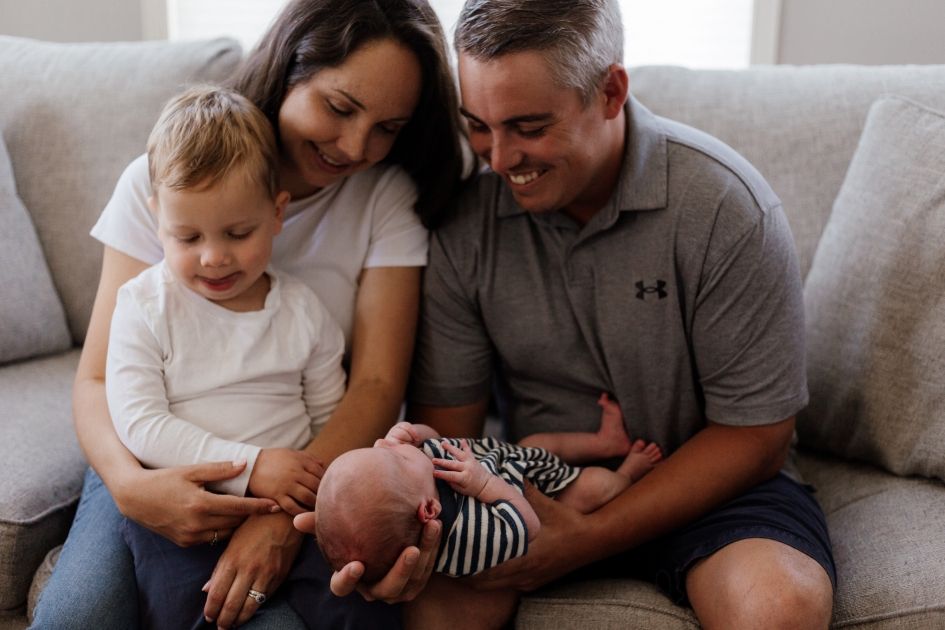 Lifestyle photoshoot of a family in their cozy living room with their newborn baby taken by a Bowmanville, ON family photographer