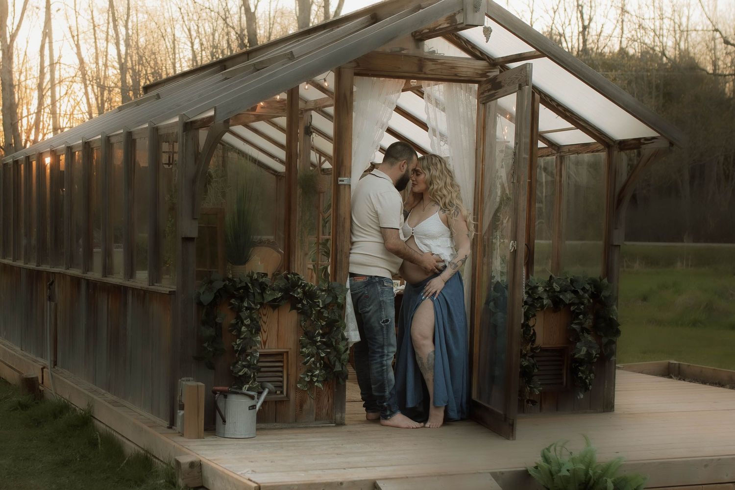 Maternity couple tenderly embracing in the doorframe of a greenhouse at sunset by Bowmanville, ON family photographer.