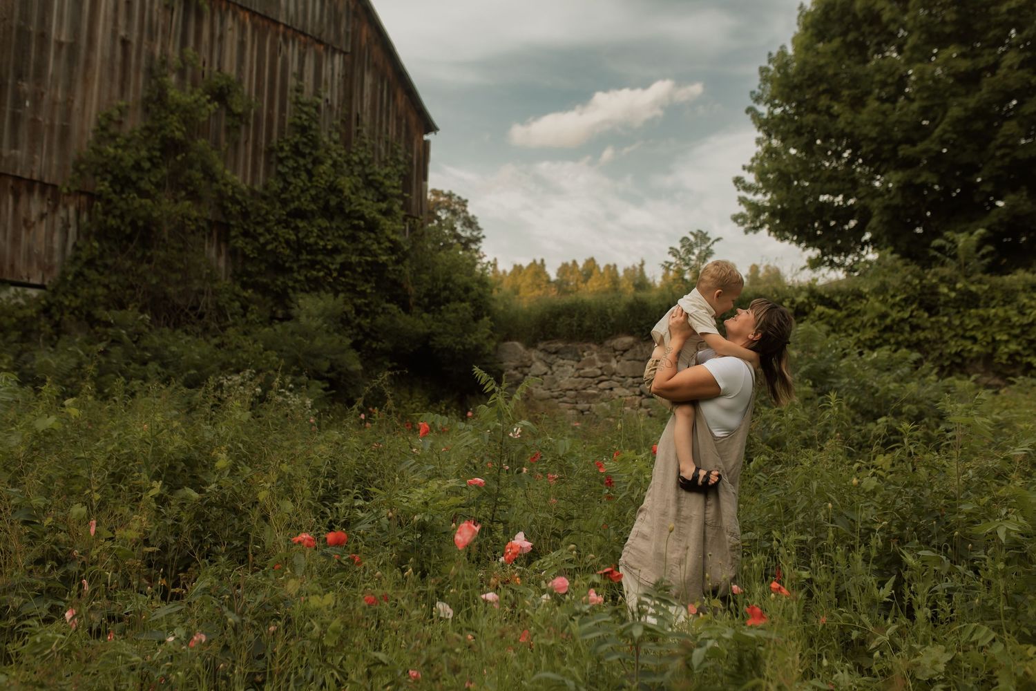 Mom and son in a field in front of a barn sharing a playful moment by Durham Region maternity photographer