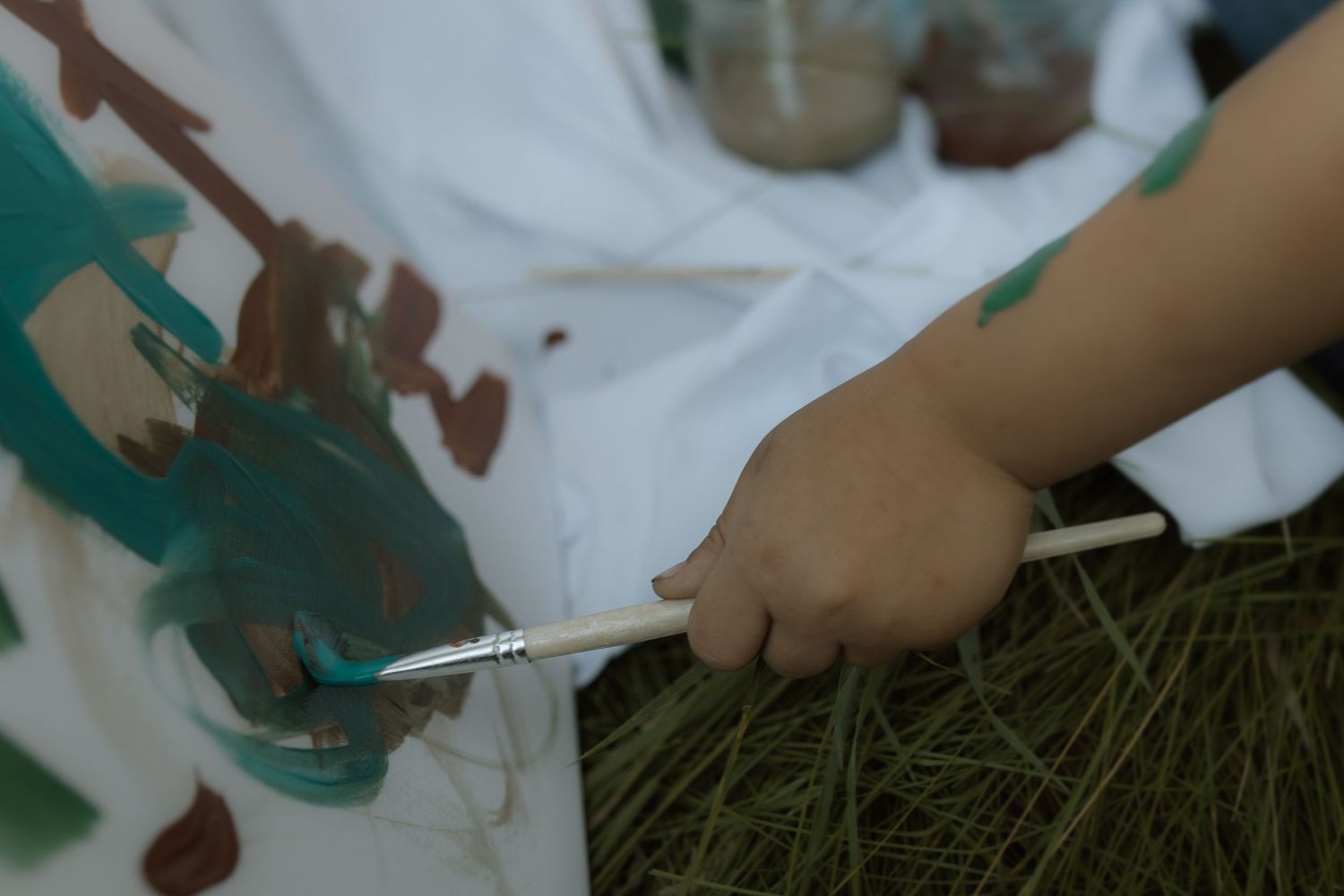 A close-up  image of a boy's hand holding a paint brush and making art on a canvas by Courtice family photographer