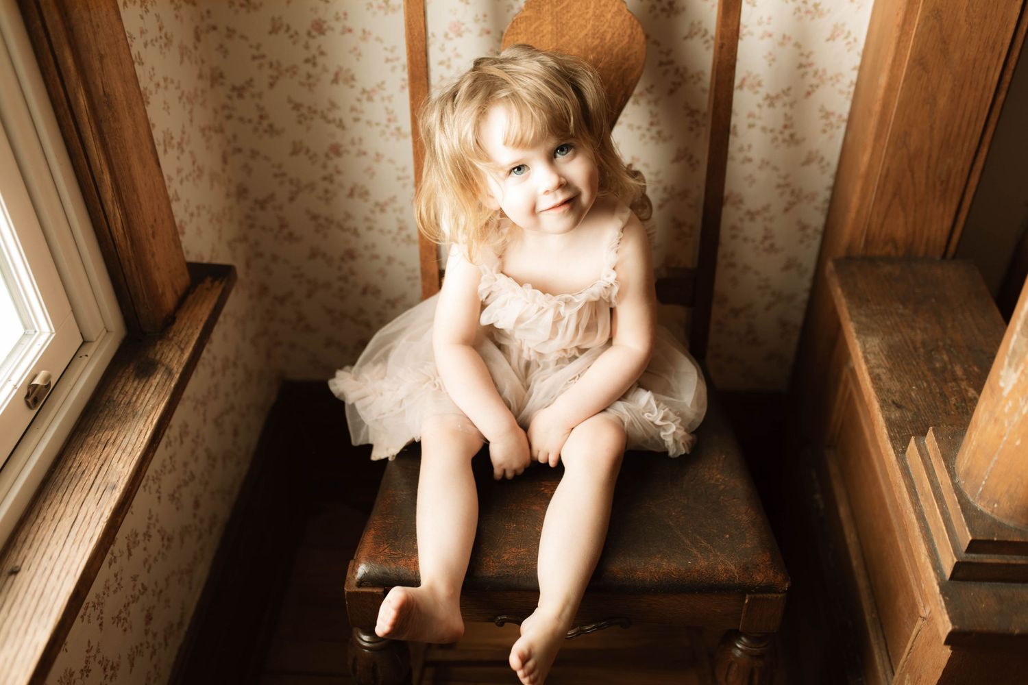 Picture of a little girl sitting on a chair with beautiful light streaming in the window by Oshawa Family photographer