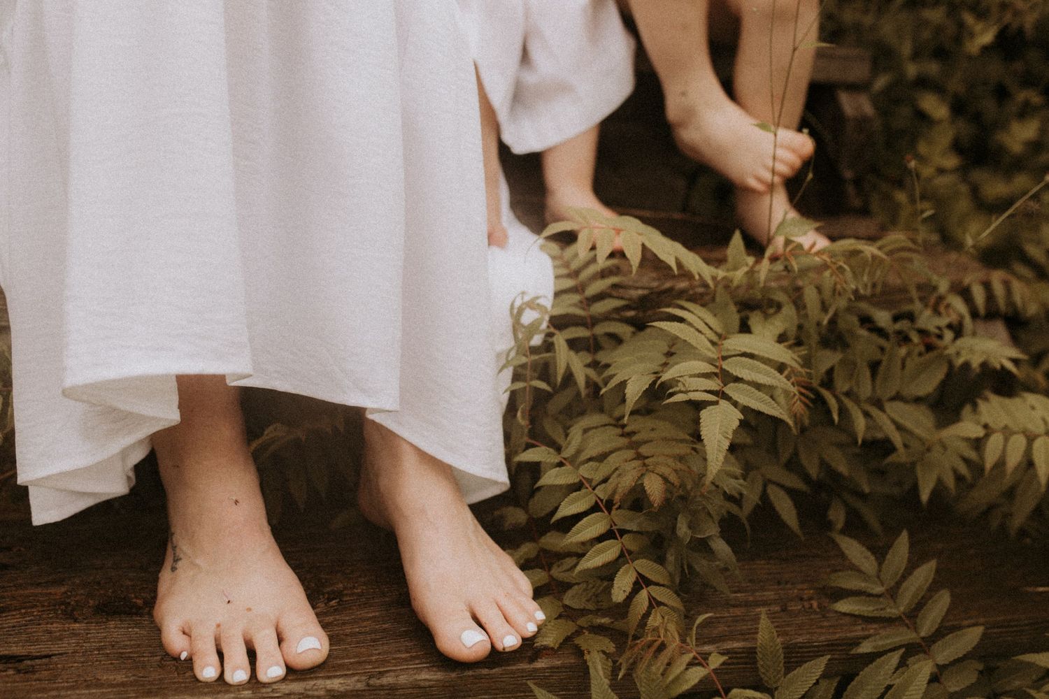 Close-up of mom and kids' feet while sitting on some rustic wooden steps at a rainy beach in Cobourg by Cobourg family photographer