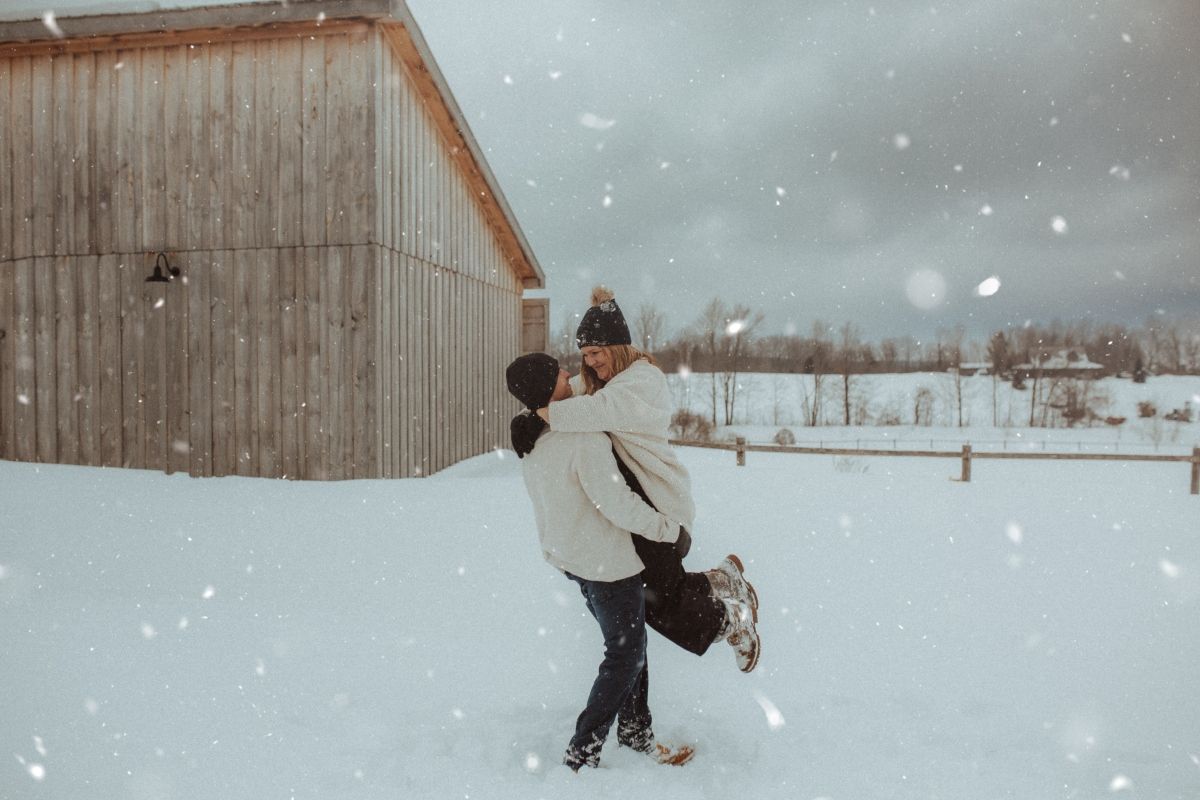 Couple playing together in the snow, laughing as they enjoy a joyful winter moment by artistic family photographer Bowmanville, ON.