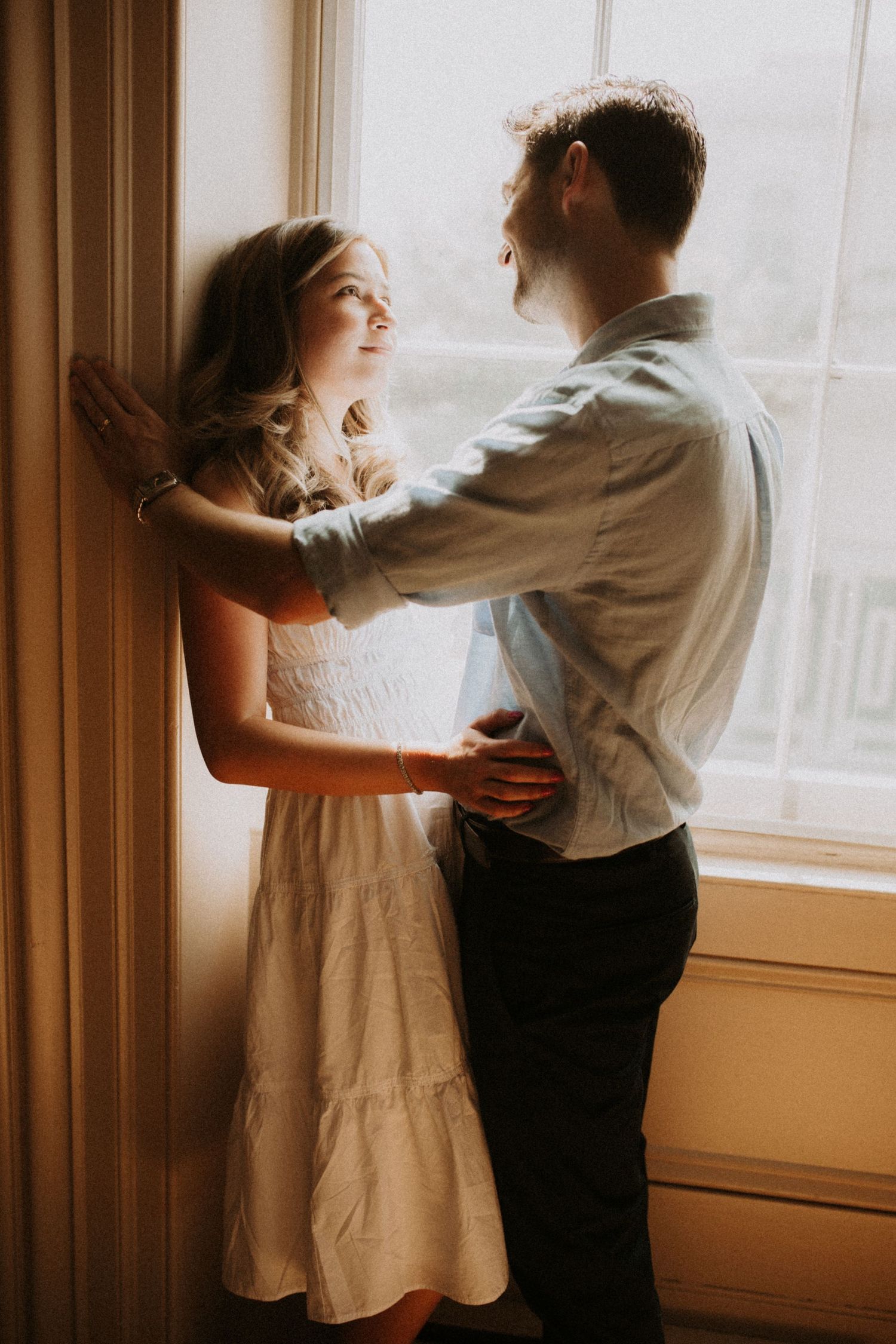 A young couple that eloped standing silhouted in the light of an old town hall window by family photographer Bowmanville, ON