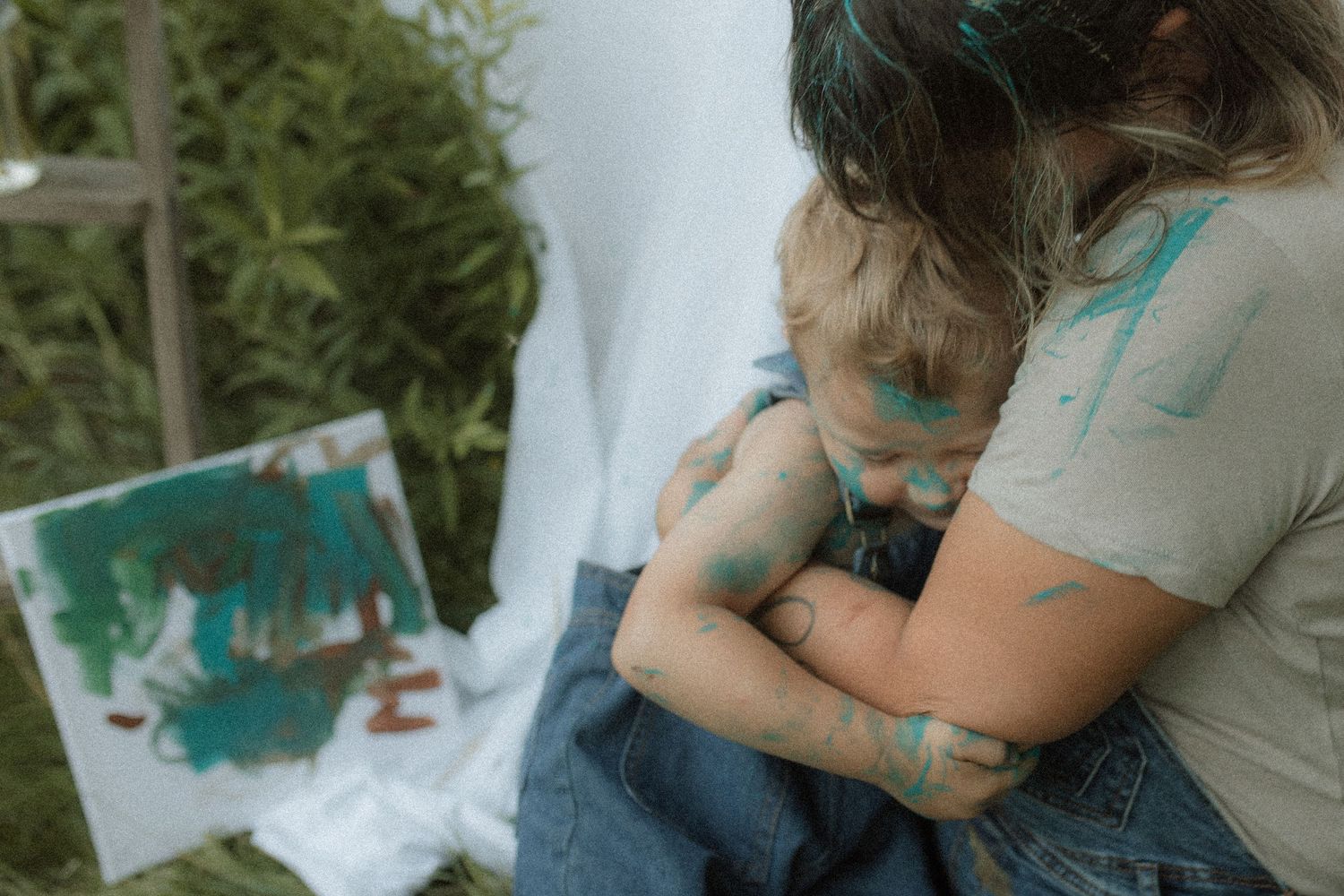 A mom and toddler share a hug during a messy painting session by Courtice family photographer