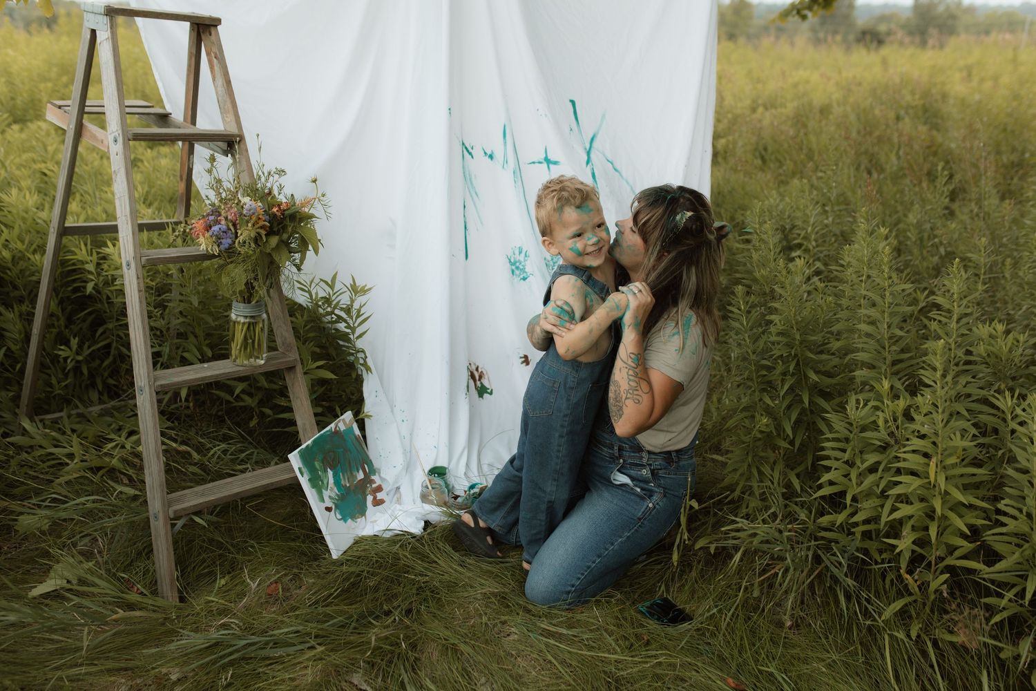 A photo of a mom and son hugging in front of a white sheet during a paint session by Courtice family photographer