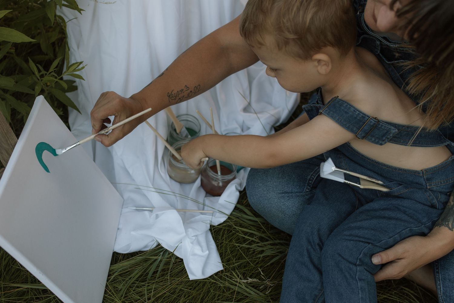 An image taken from above of a son and mom painting on an easel by Courtice family photographer