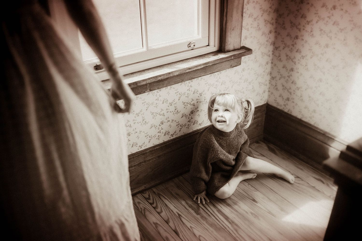 Young girl sitting on a wooden floor during a lifestyle family photography session in Durham Region, Ontario