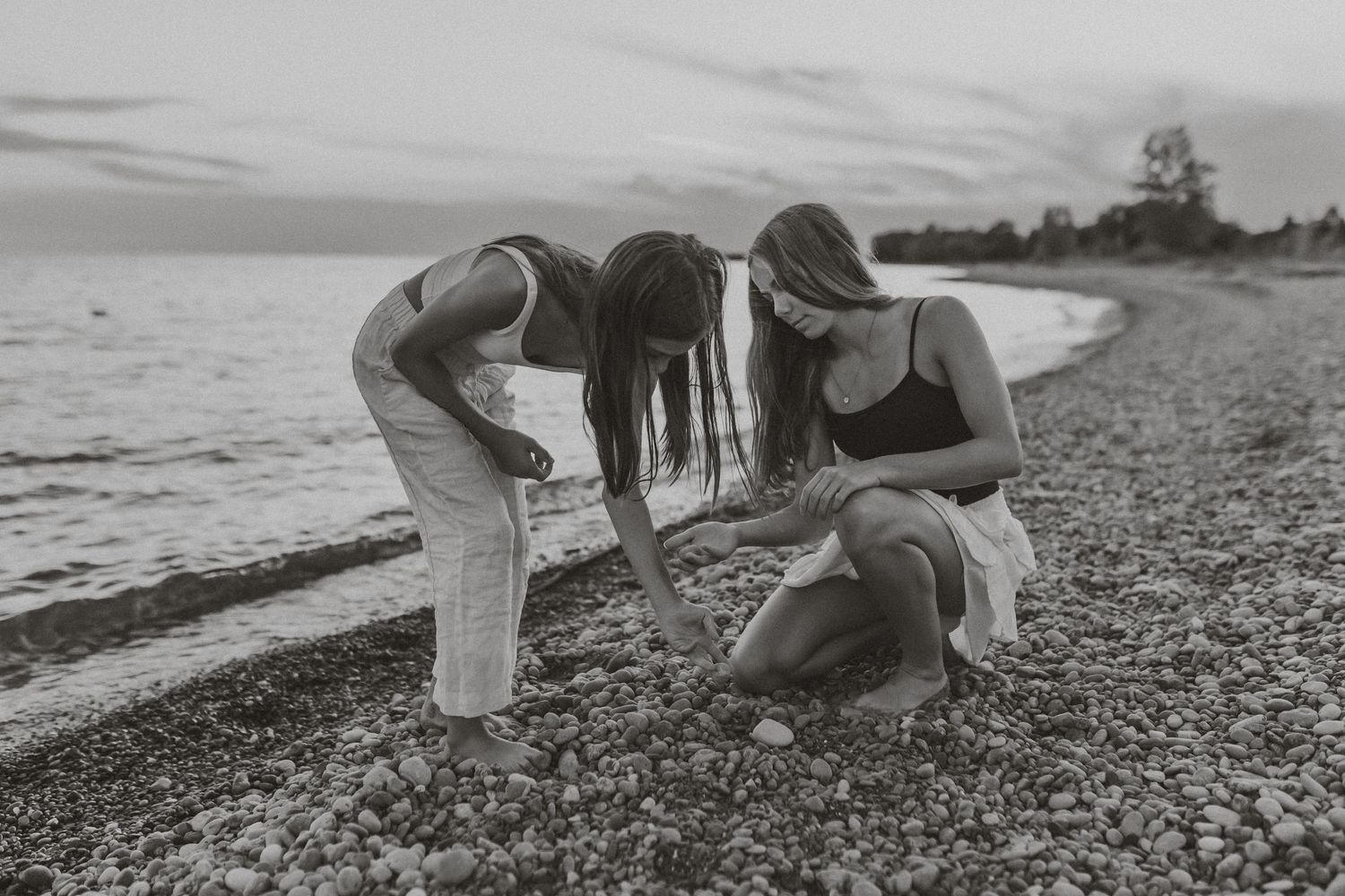 People sitting and relaxing on a rocky beach shore in black and white in Cobourg, ON