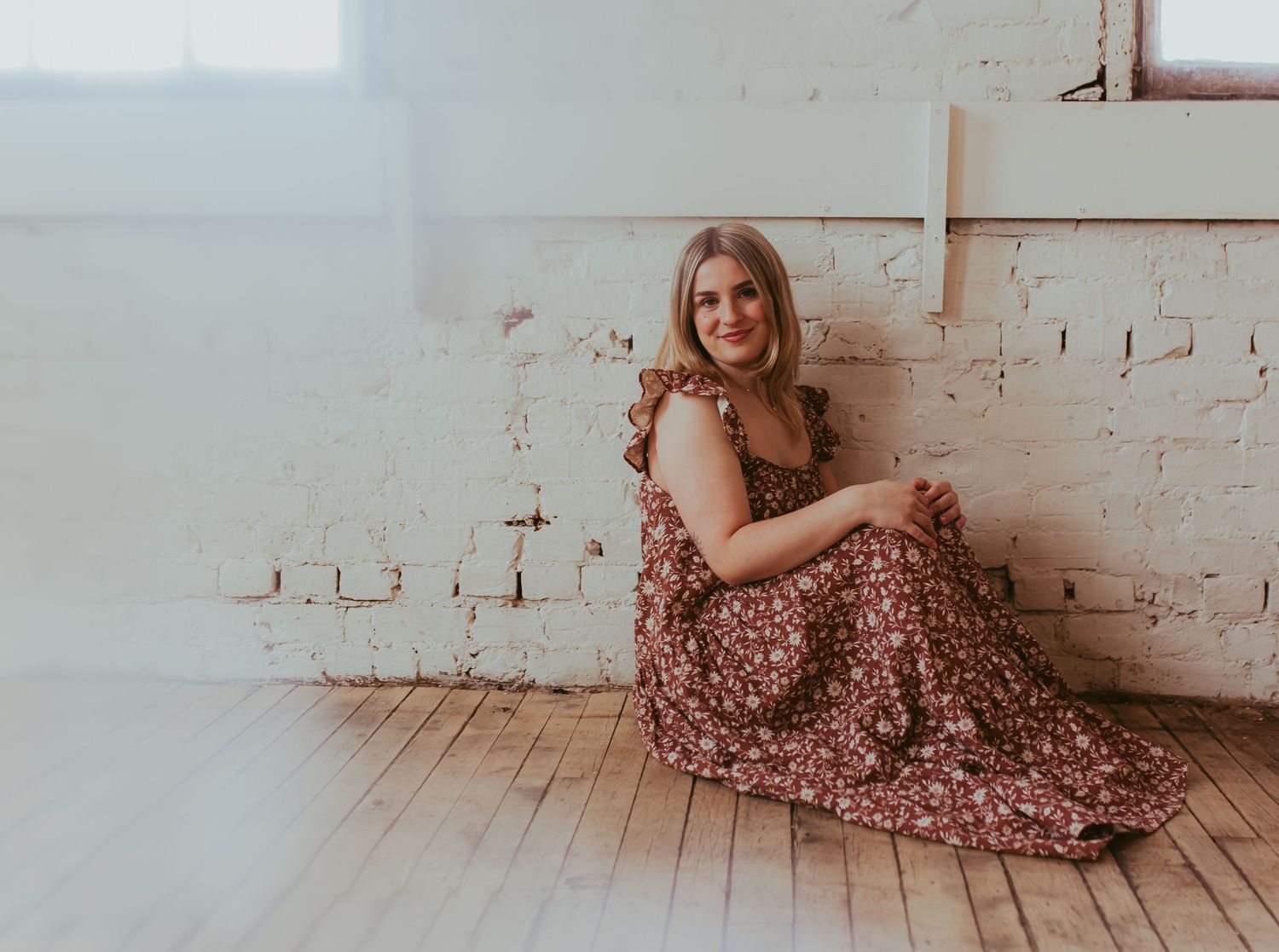 Floral dress photographed in sequence showing relaxed poses on wooden floor.