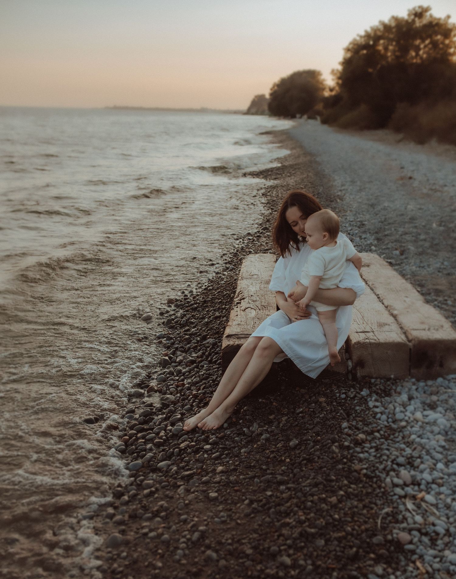 Motherhood session at the beach with her young child enjoying the waves and the sunset.