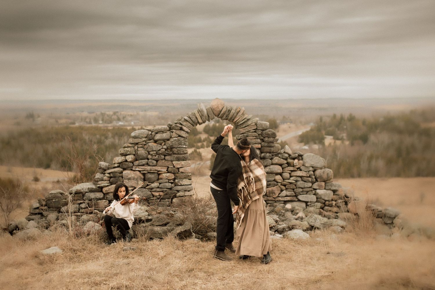 Family dancing in a field by an old stone ruin by Bowmanville, ON family photographer.