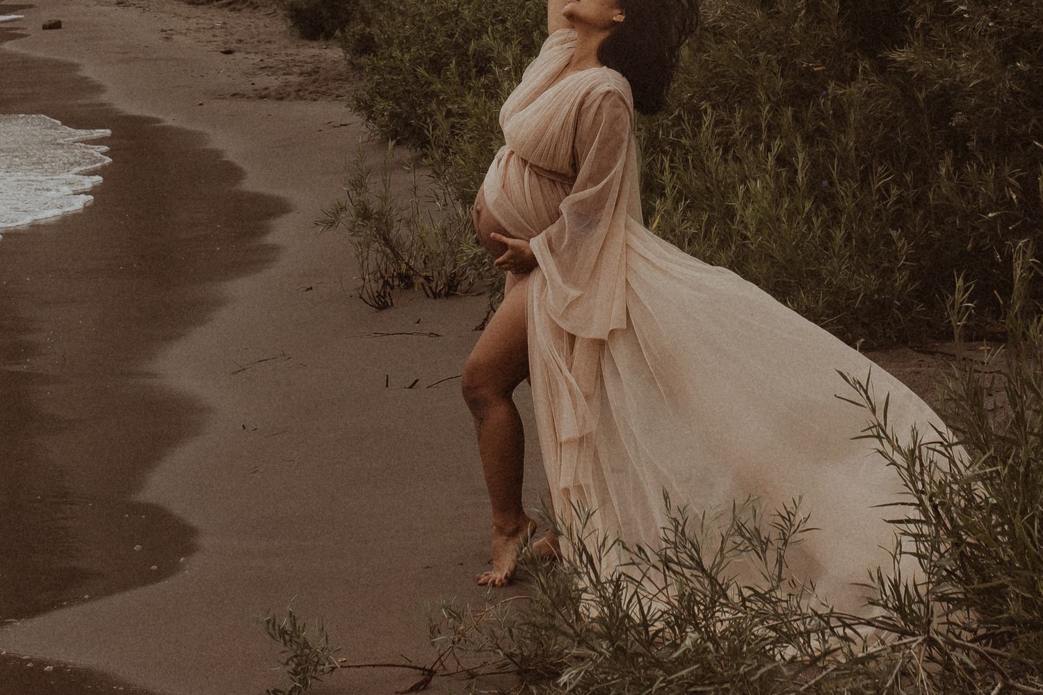 A pregnant mom standing on the Scarborough Bluff's beach on a windy day by Durham Region maternity photographer
