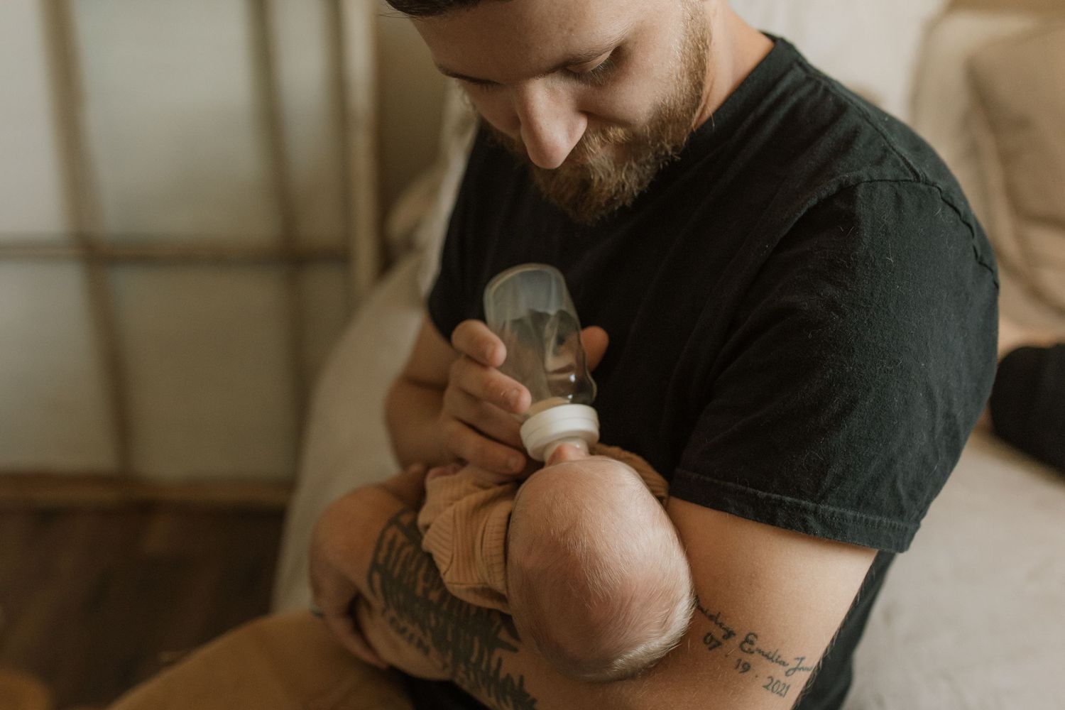 Dad bottle-feeding his newborn son in a warm studio session by newborn photographer in Bowmanville, ON