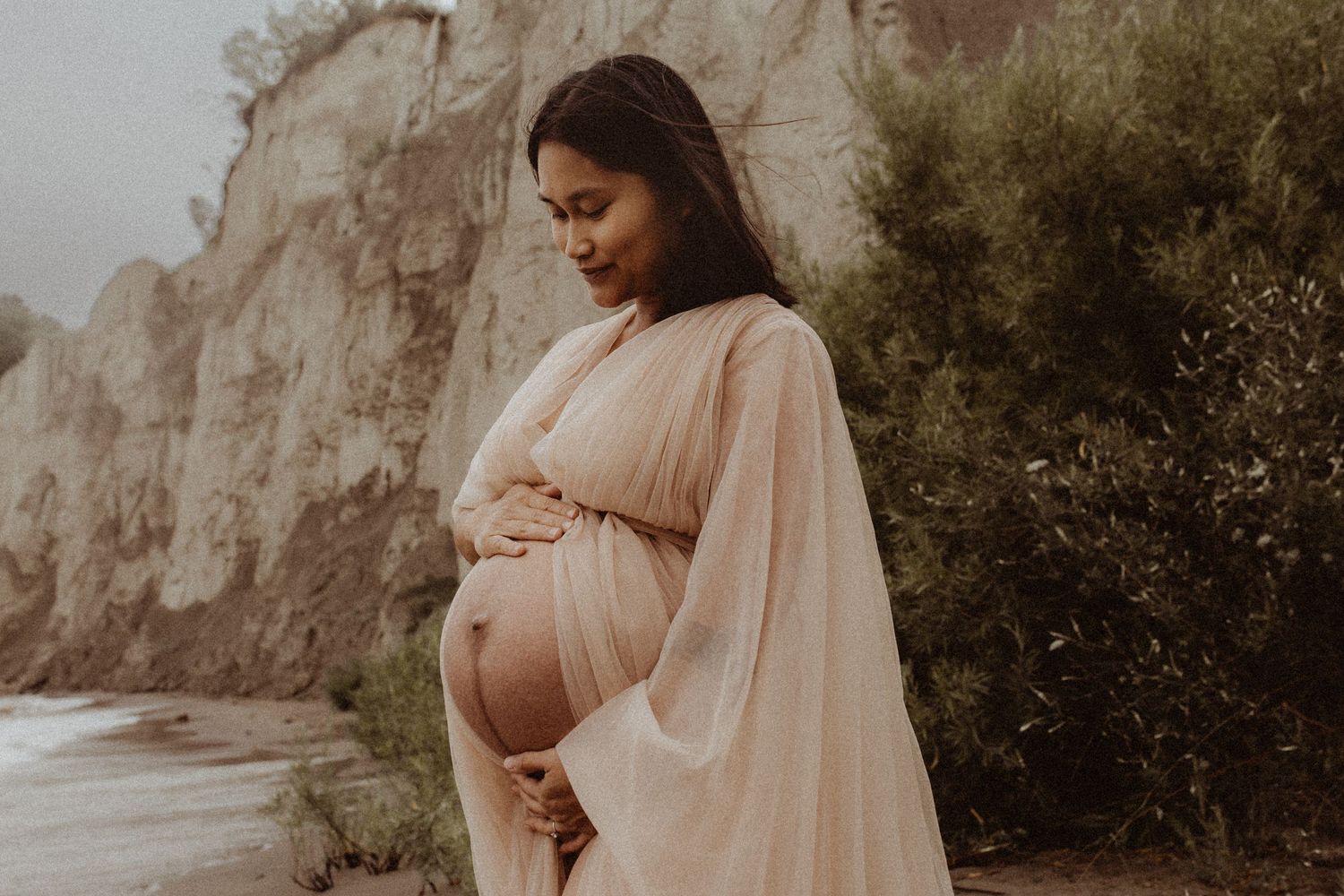 A mom looks lovingly down at her baby bump during a maternity session by Durham Region maternity photographer