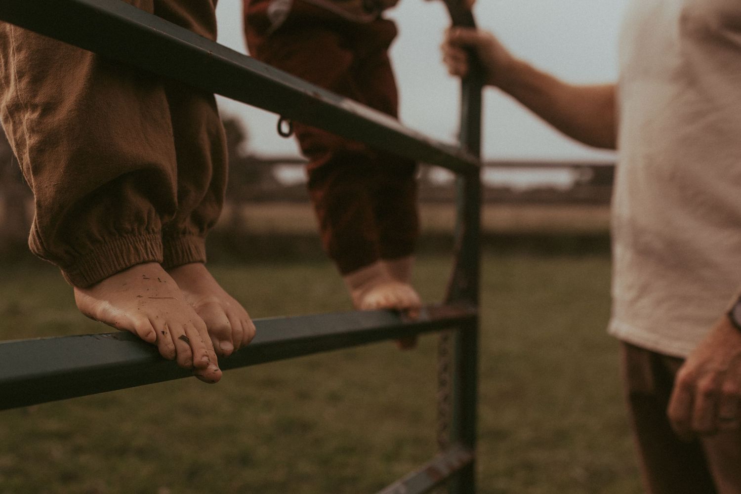 Close-up image of boys' feet climbing a gate as their dad assists by Durham Region family lifestyle photographer.