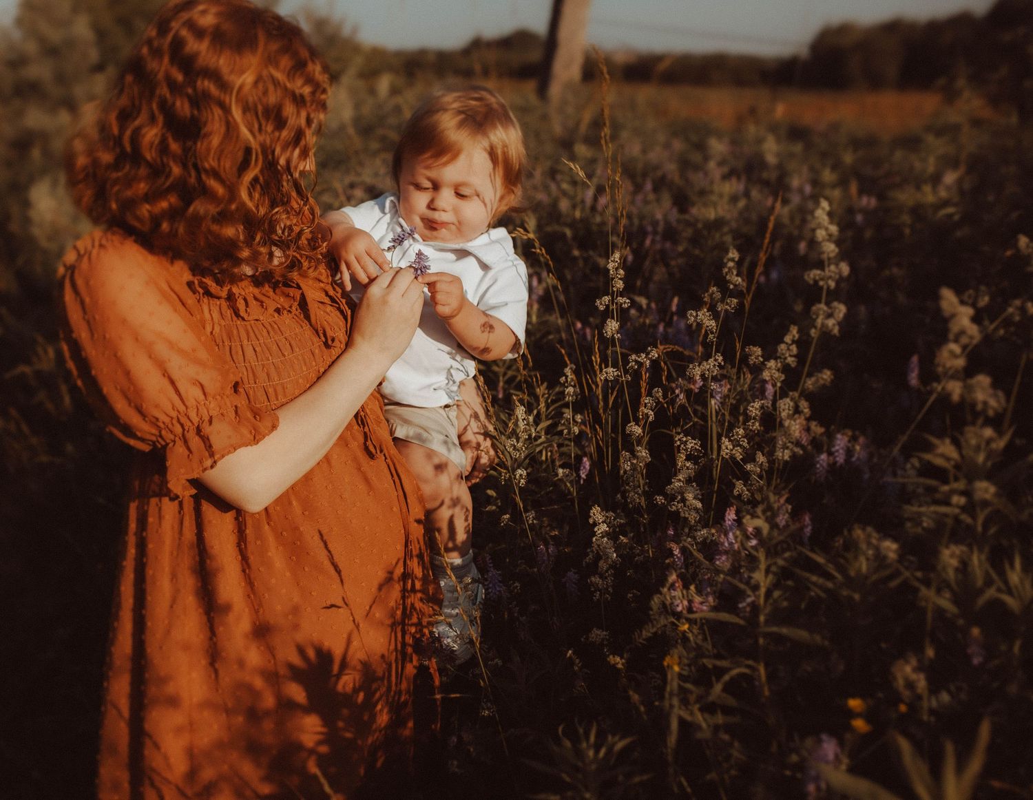 Mom with baby in a field of wildflowers in the early morning light.