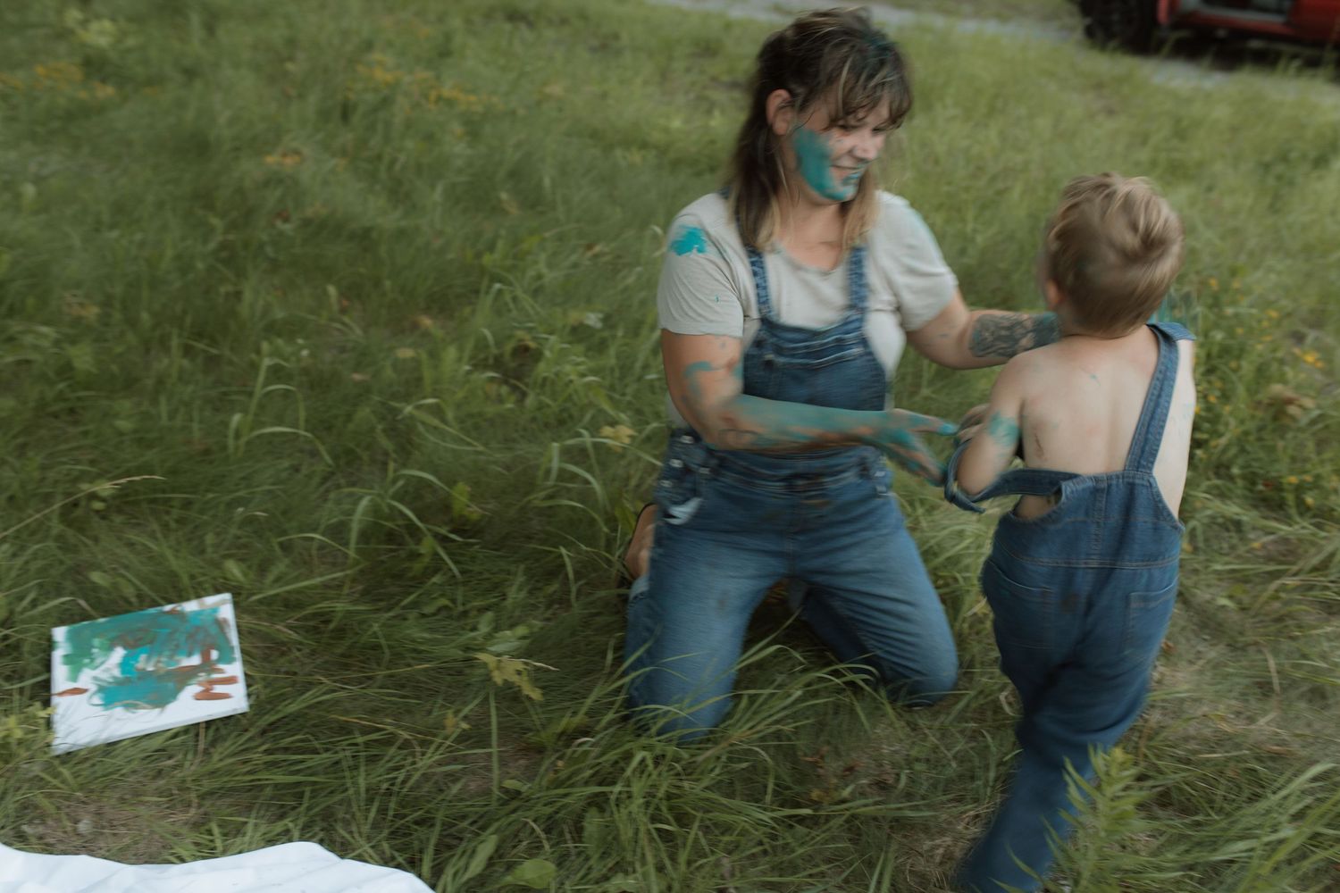 A photo of a mom and son playing in the grass after a busy paint session by Courtice family photographer