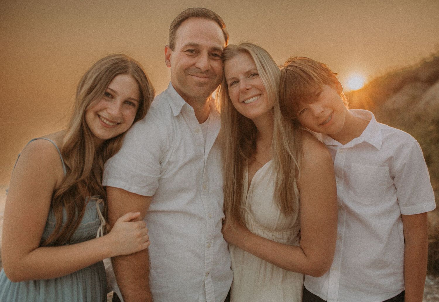 Happy family during golden hour at the beach smiling at the camera by Durham Region maternity photographer
