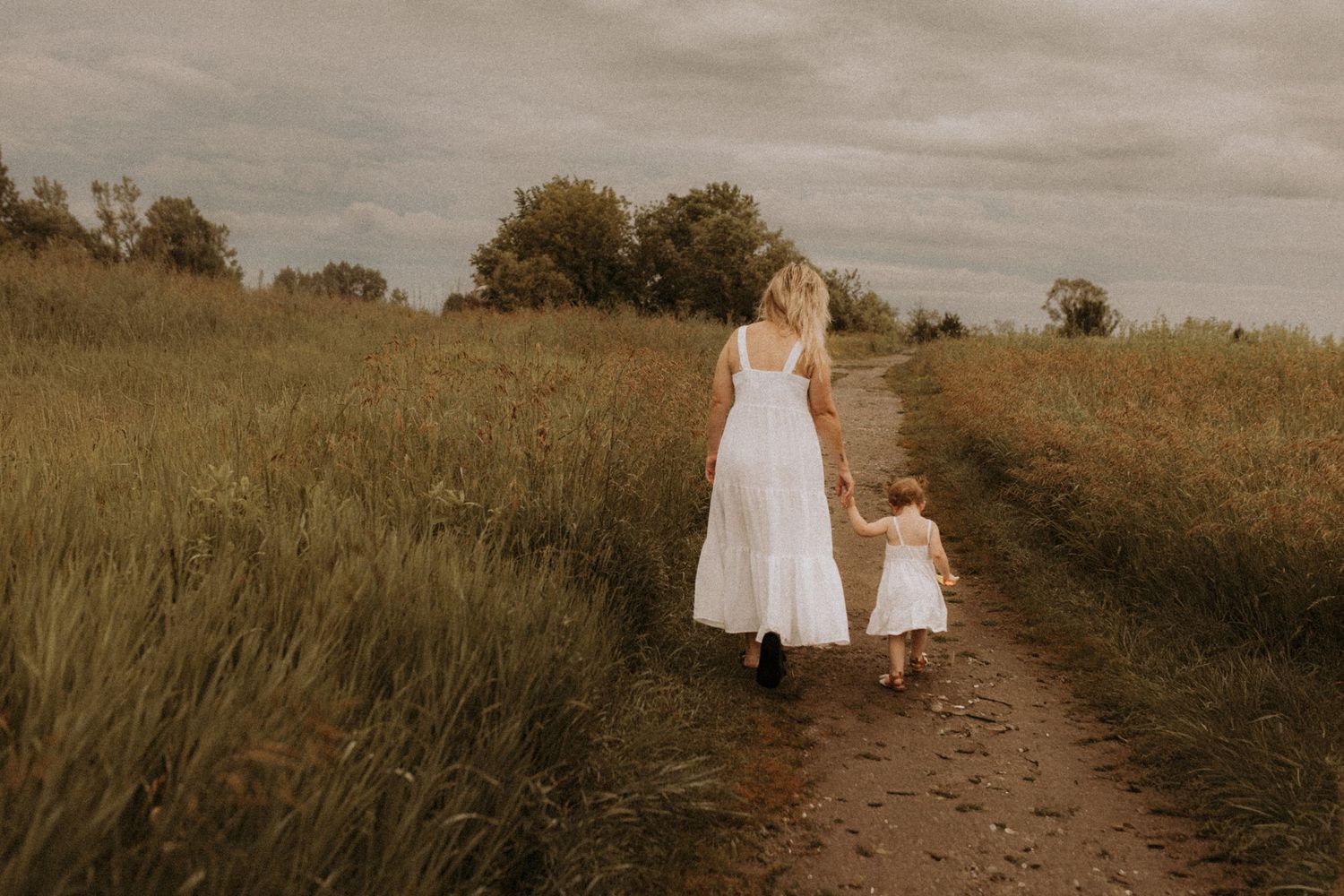 Mom and kids wearing white near a rustic fence near the beach by Cobourg family photographer