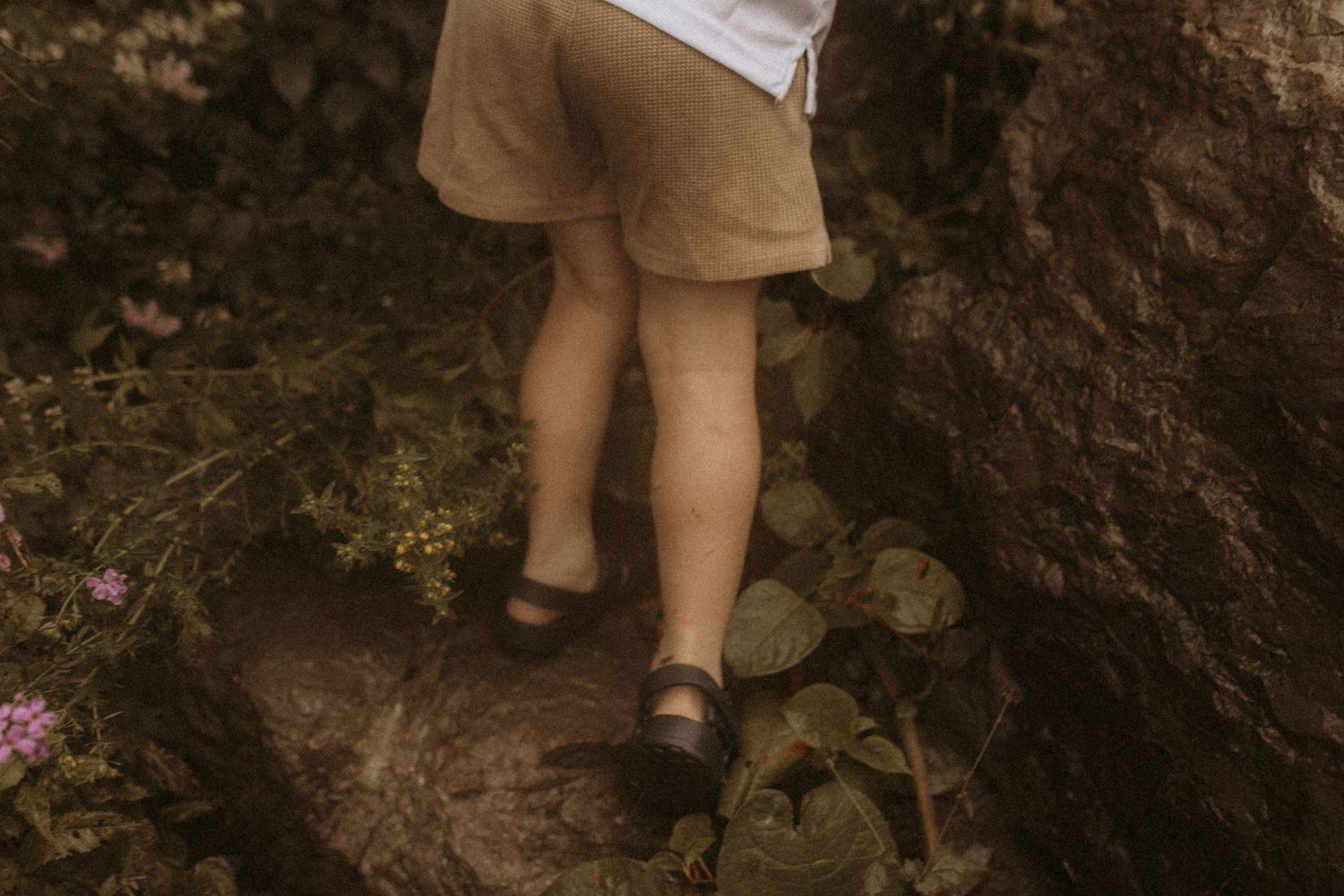 Photo of a boy's legs while he is climbing rocks near a beach by Cobourg family photographer