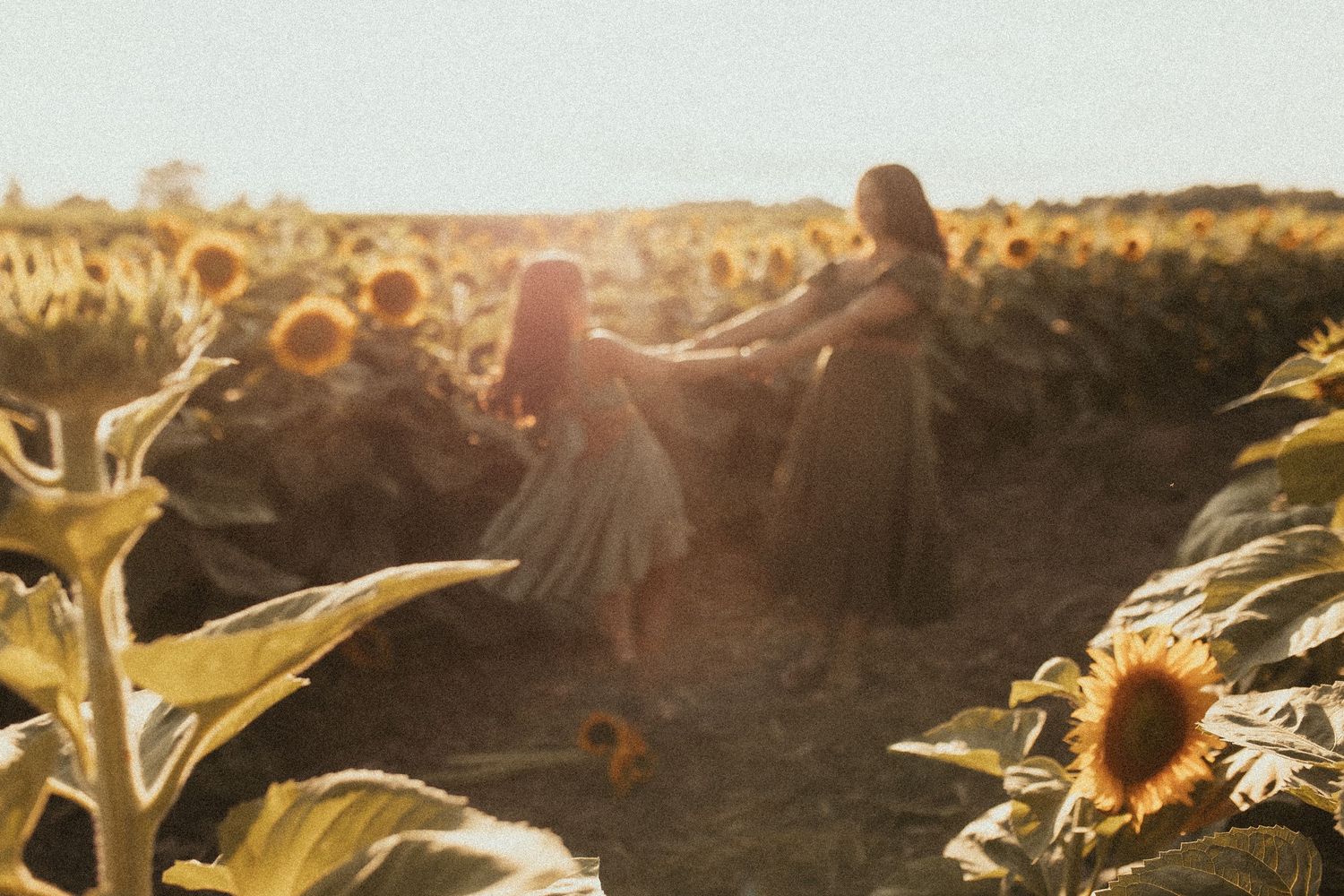 A mom and daughter dancing together in a sunflower field by Durham Region family photographer