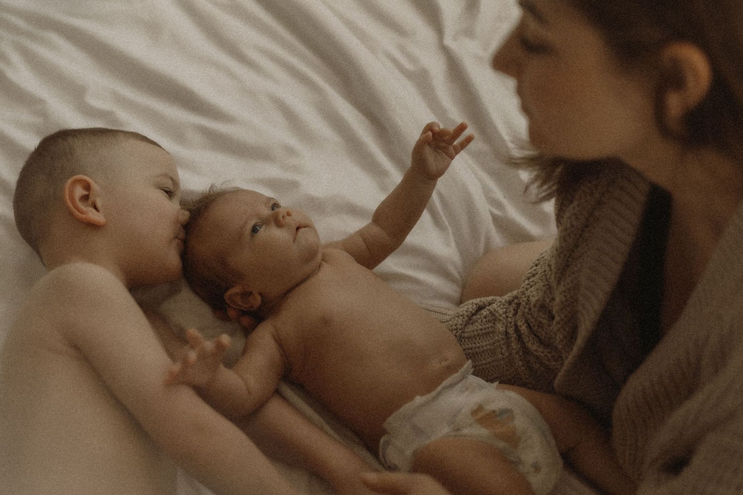 Mom with newborn baby and big brother sharing a tender moment together on the bed by Bowmanville, ON family photographer