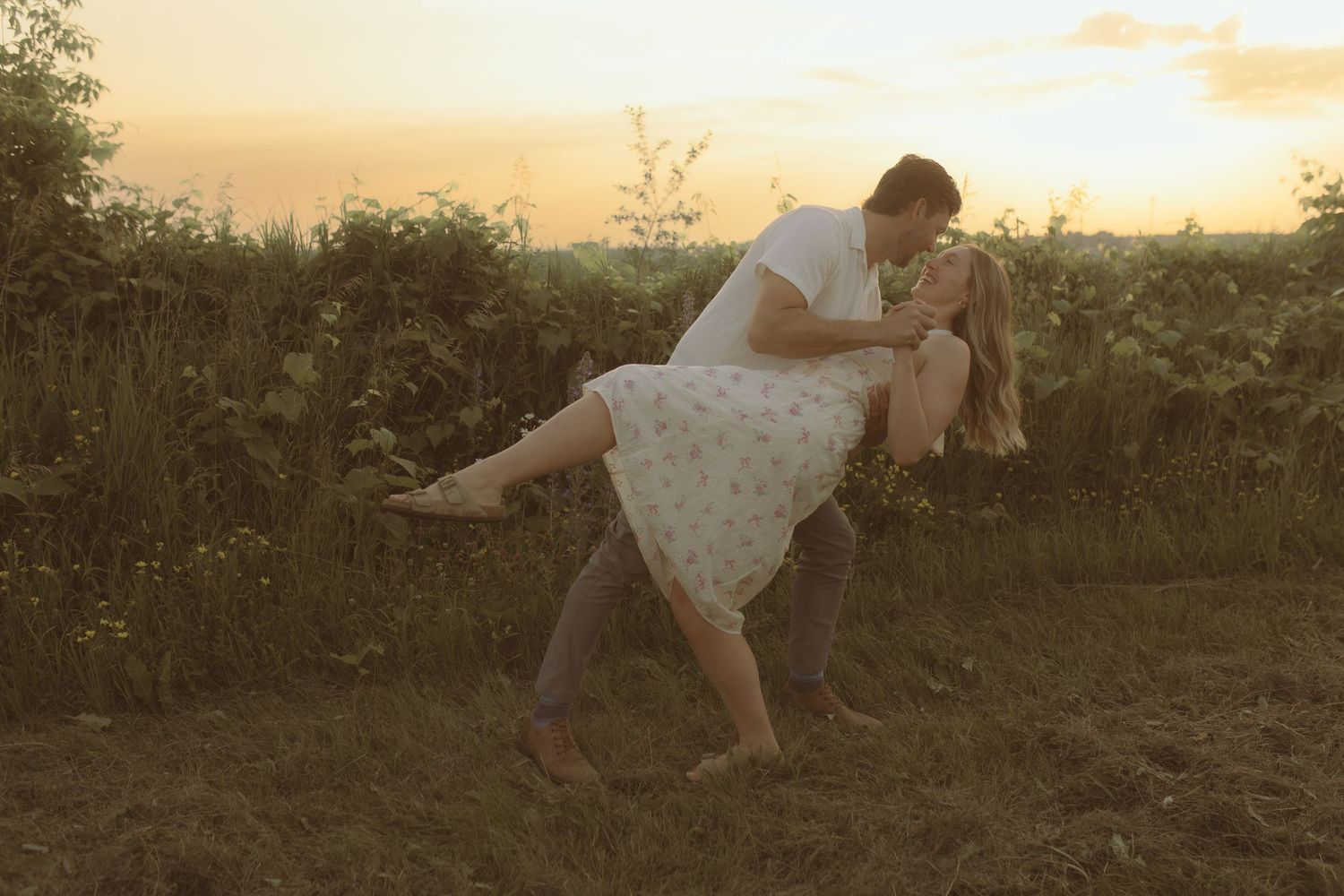 Cinematic engagement session for a couple at sunset in a field dancing and laughing by Cobourg Wedding and Elopement Photographer
