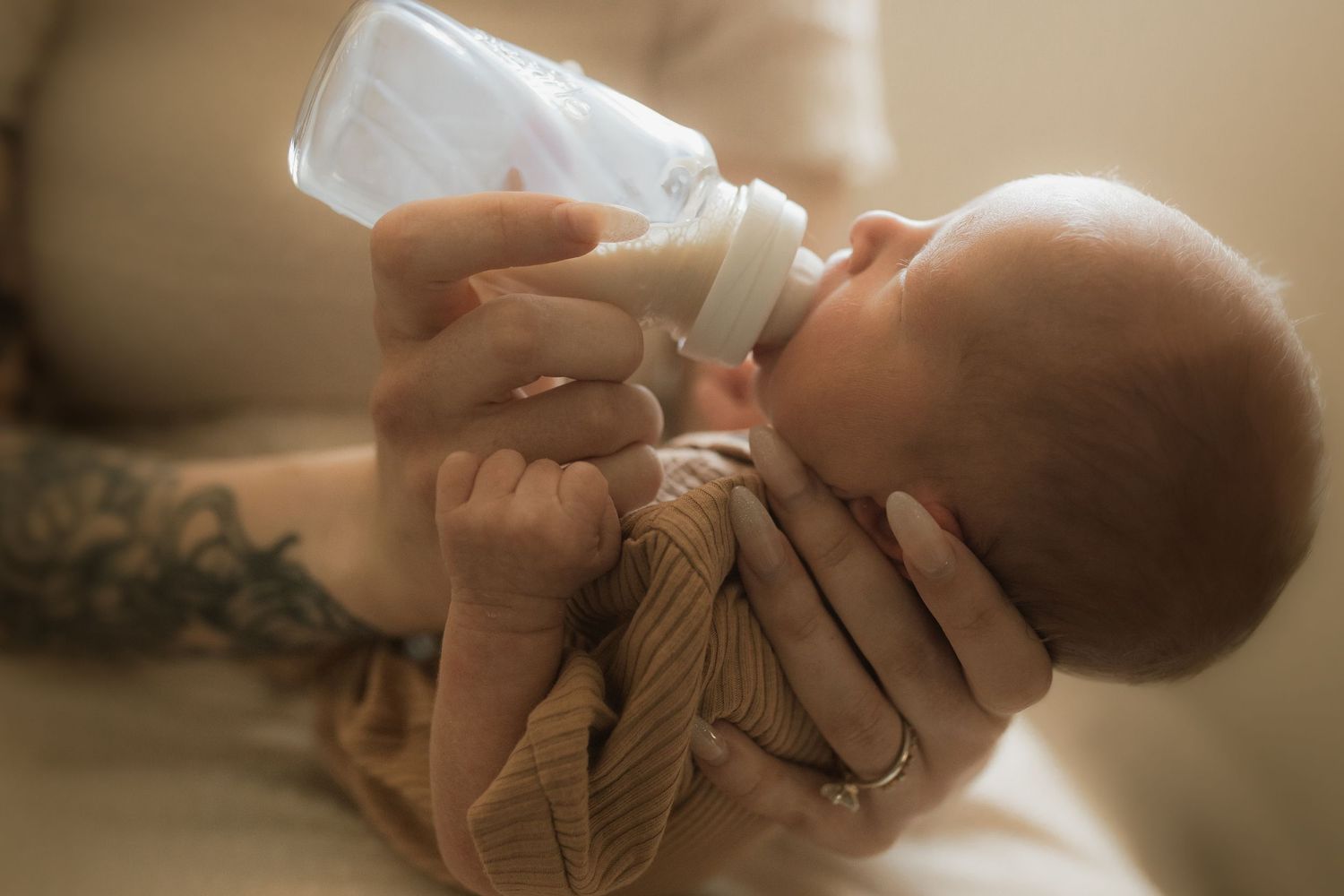 Close-up of a newborn baby drinking from a bottle on the mom's lap in a cozy studio by newborn photographer in Bowmanville, ON