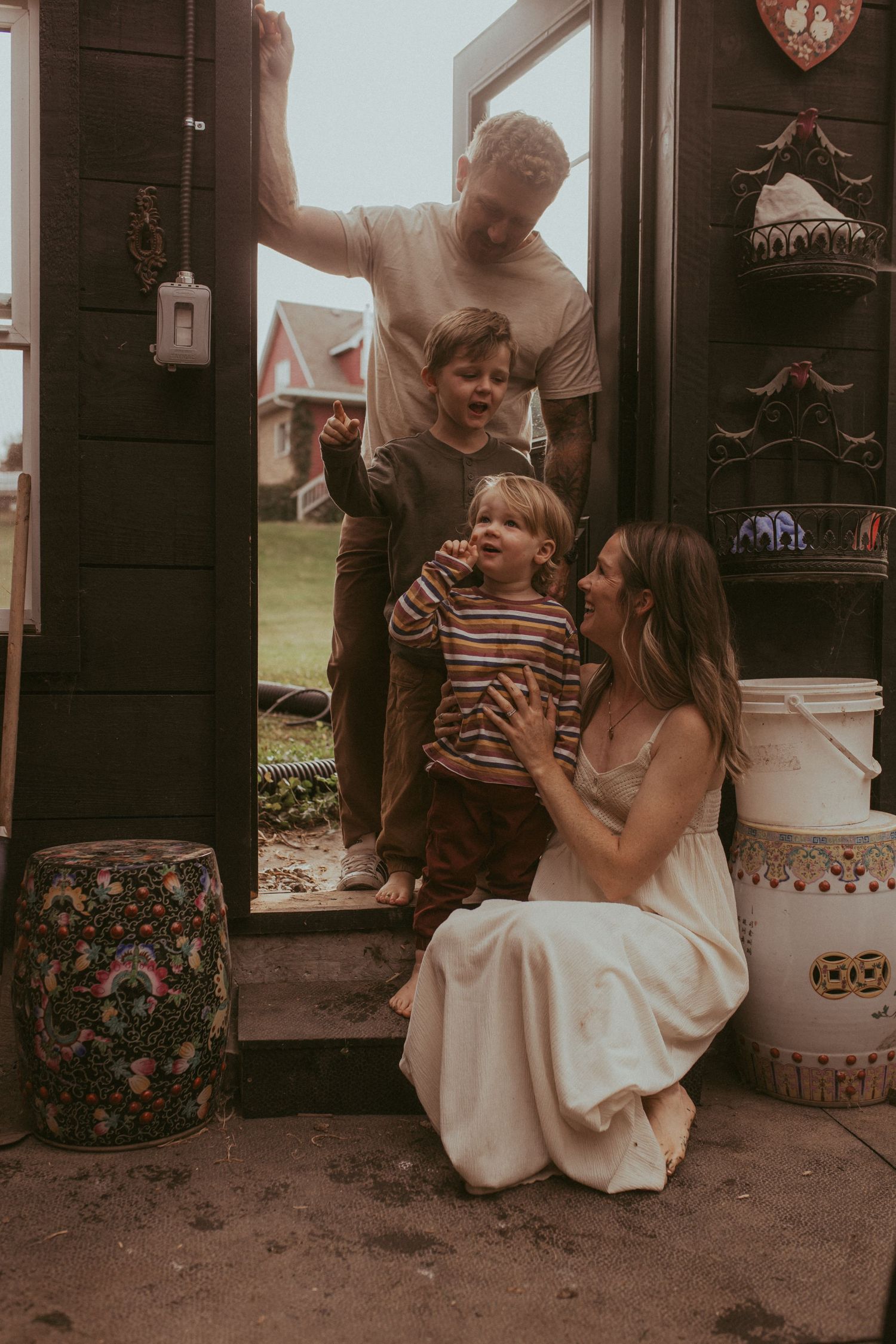 A family is grouped together in the doorway of a greenhouse by Durham Region family lifestyle photographer