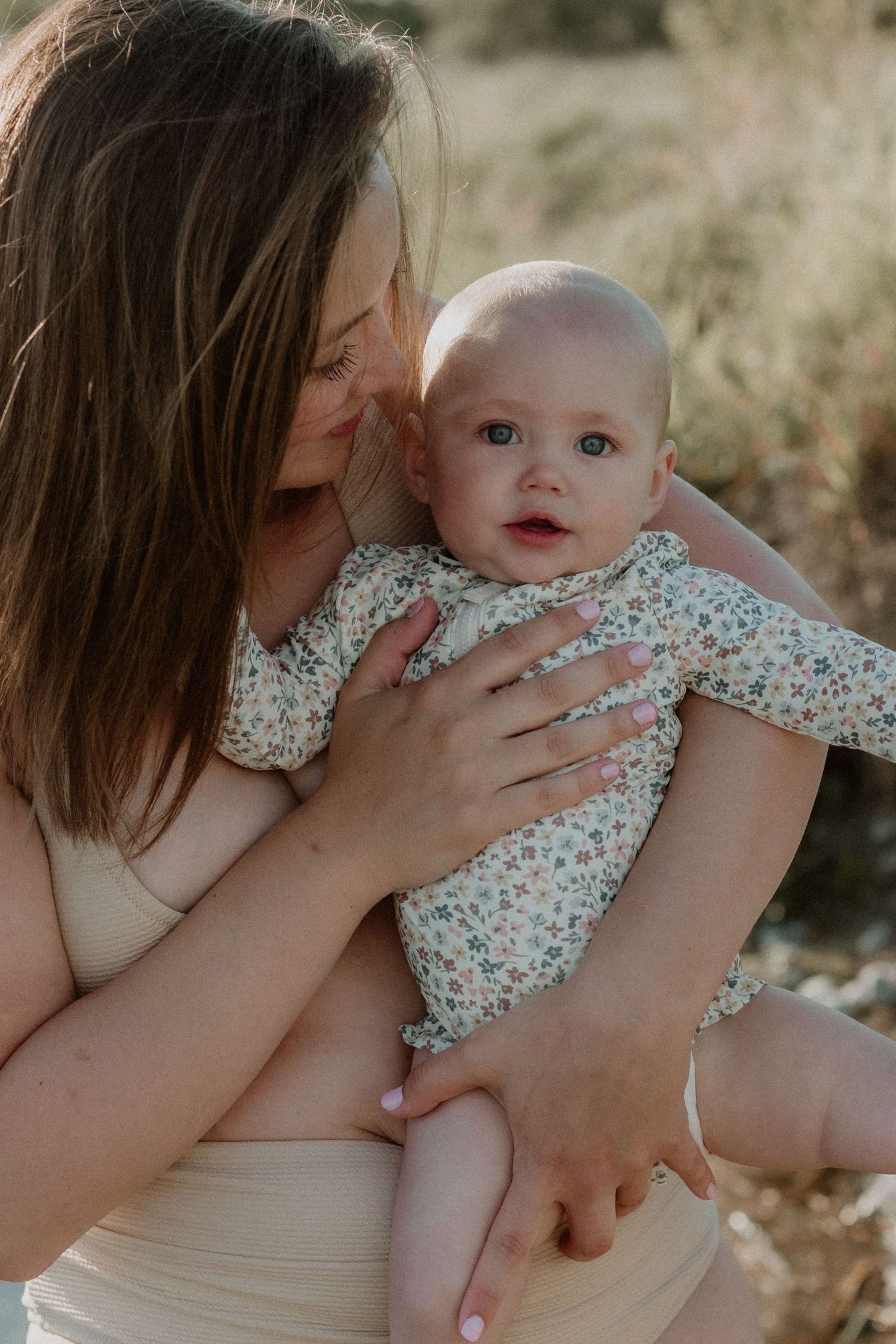 Tender moment between parent and baby in floral dress against natural outdoor setting taken by your Bowmanville, ON family photographer