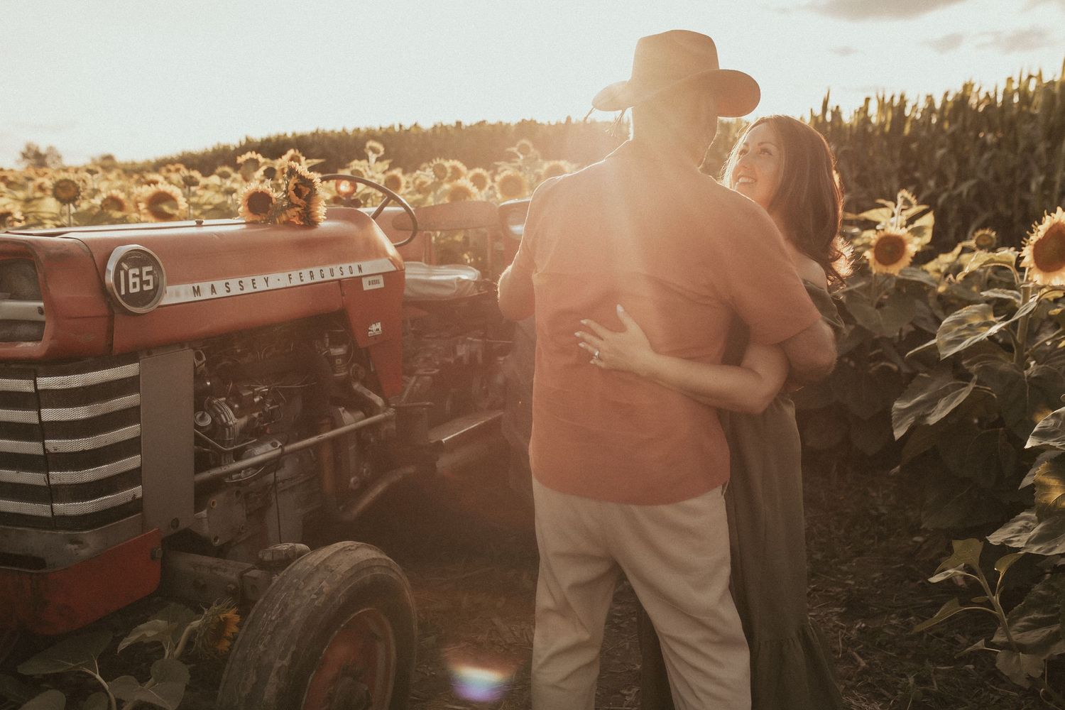 A photo of a couple dancing in the golden light near an antique tractor by Durham Region family photographer