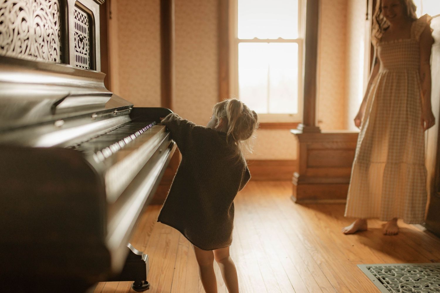 Little girl playing the piano as her mother looks on by Bowmanville maternity photographer
