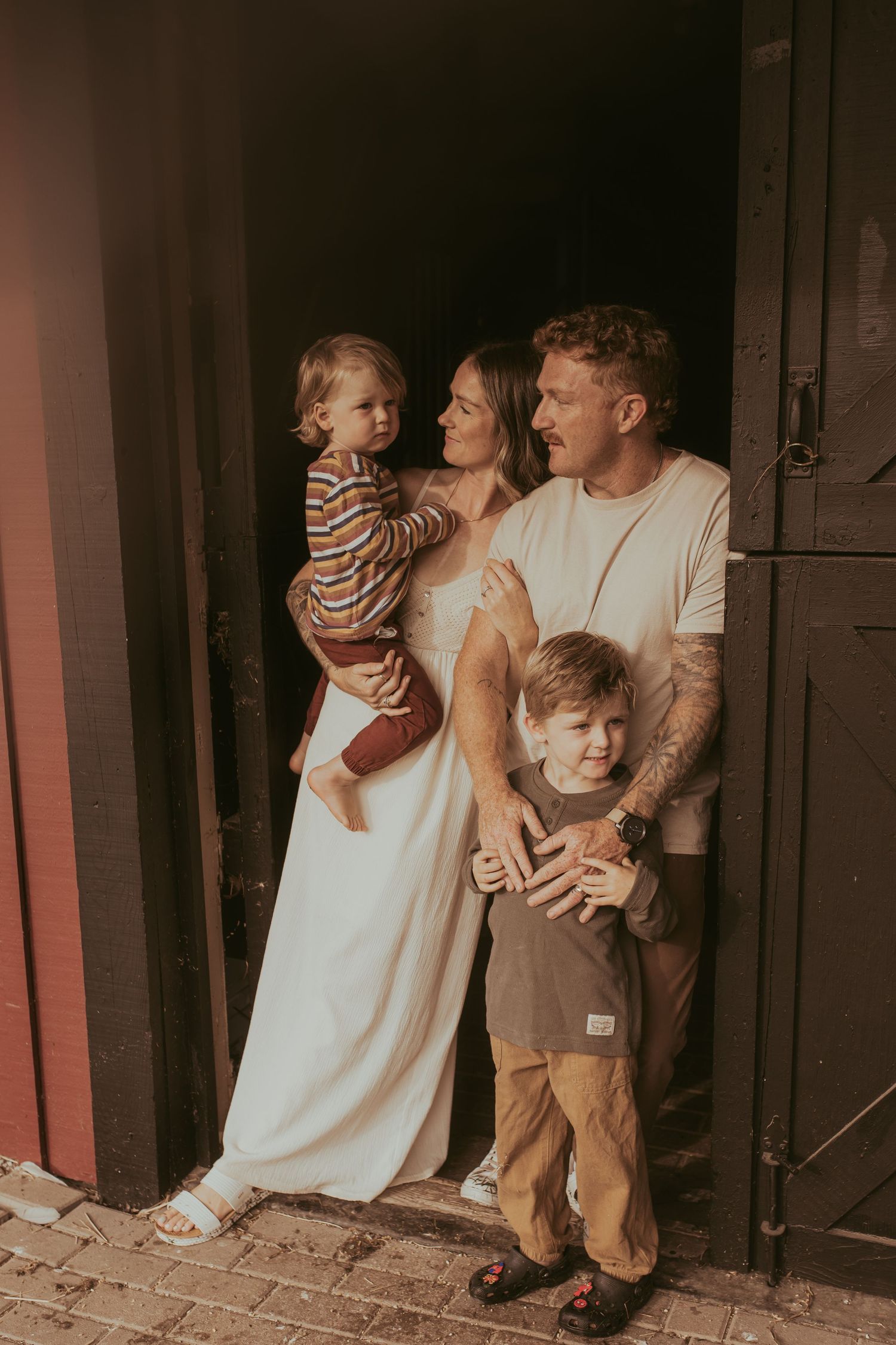 A young family stands together in the doorway of a barn by Durham Region family lifestyle photographer