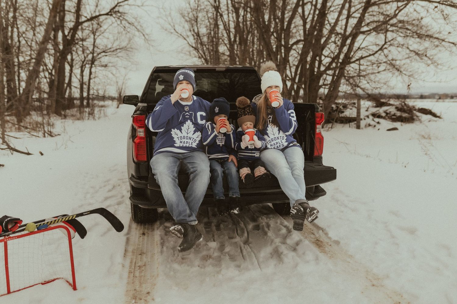 Newcastle, ON Family photographer took this photo of a family wearing hockey jerseys and drinking hot chocolate in the back of a truck