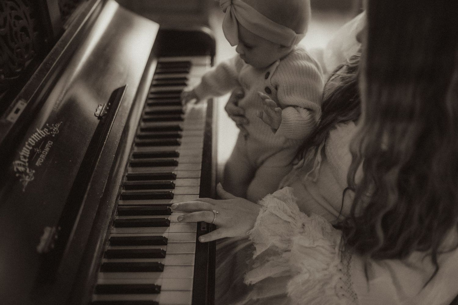 black and white image of a mom with her baby playing the piano by an Orono, ON family photographer