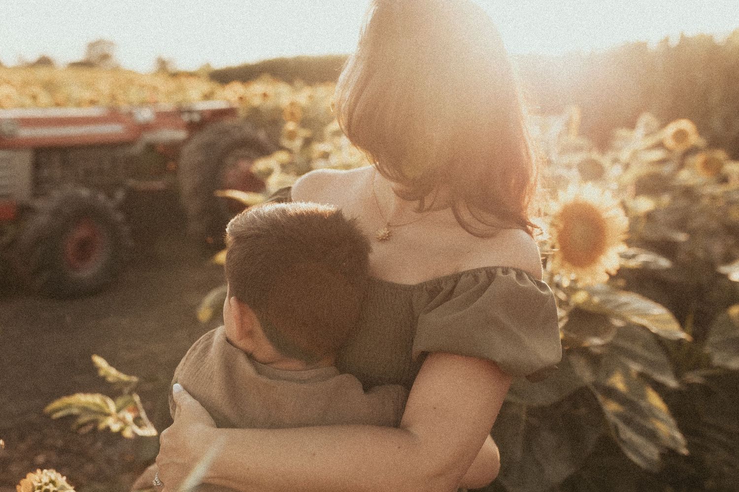 A mom and son share a quiet moment as they gaze together out over the sunflower fields by Durham Region family photographer