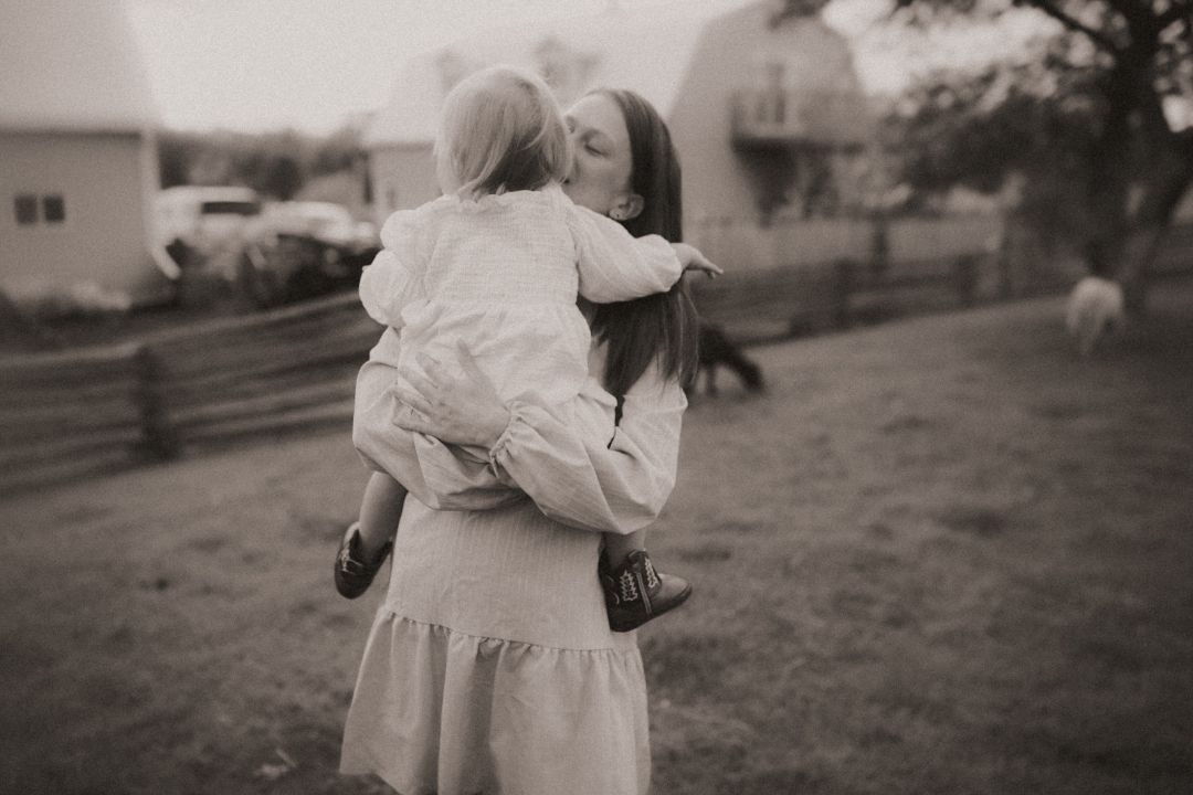 Candid family session with a loving moment captured between a mom and her baby on a farm.