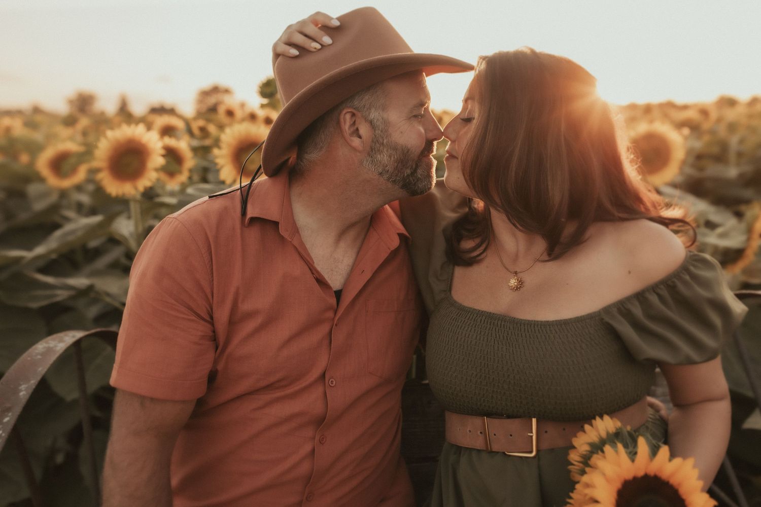A couple kissing in a sunflower field at sunset by Durham Region family photographer
